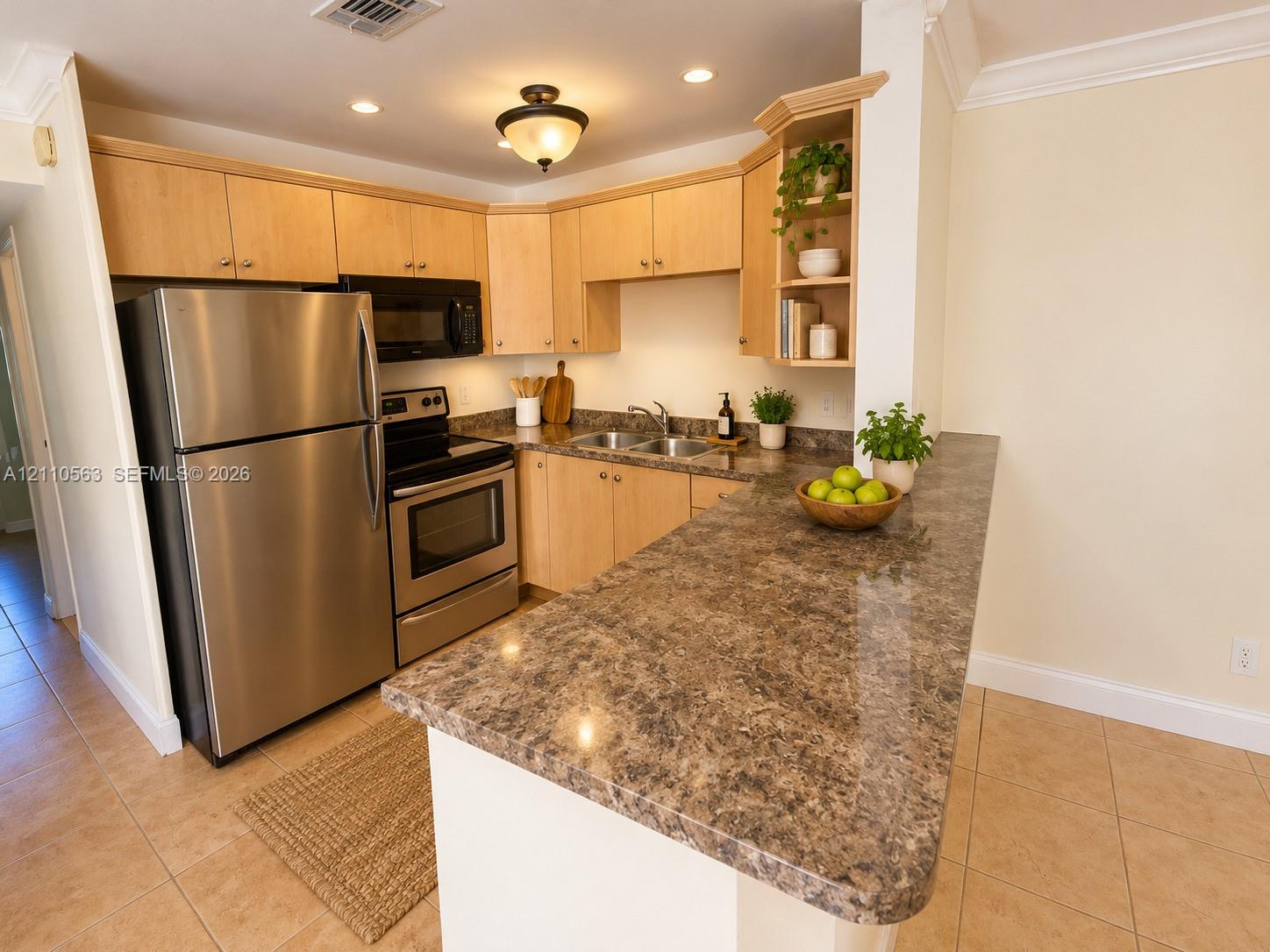 Kitchen featuring wood cabinetry, stainless steel appliances, a peninsula with stone-finish countertops, ceramic tile flooring, and recessed lighting Kitchen featuring wood cabinetry, stainless steel appliances, a peninsula with stone-finish countertops, ceramic tile flooring, and recessed lighting