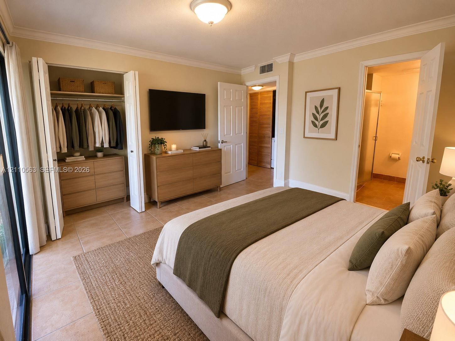 Bedroom featuring tile flooring, crown molding, two-panel interior doors, and a built-in reach-in closet with folding doors Bedroom featuring tile flooring, crown molding, two-panel interior doors, and a built-in reach-in closet with folding doors