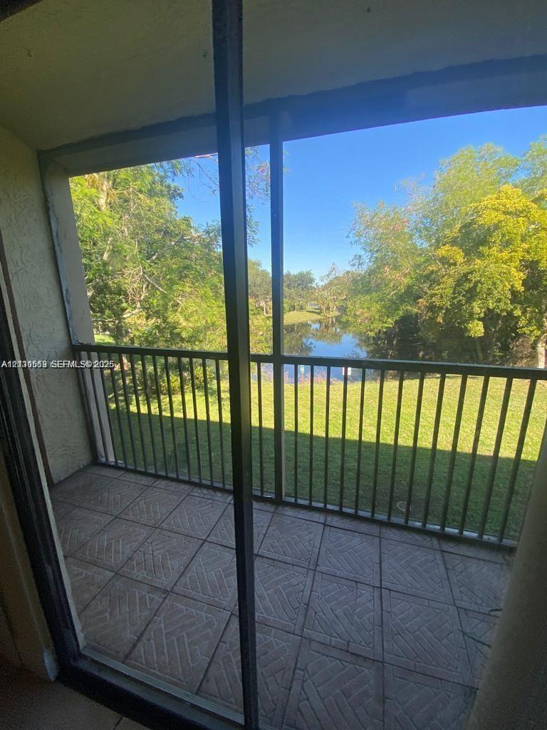 Screened-in balcony featuring ceramic tile flooring, a metal railing, and a backdrop of mature trees and water Screened-in balcony featuring ceramic tile flooring, a metal railing, and a backdrop of mature trees and water