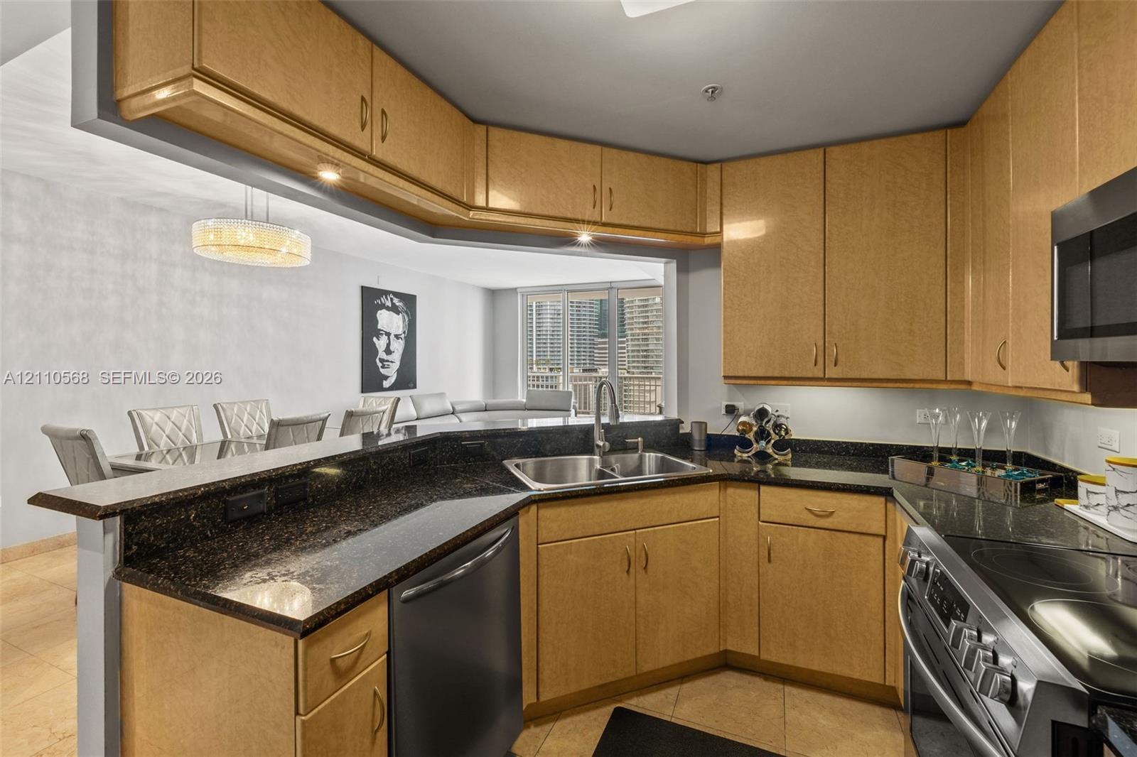 Kitchen featuring light-finish cabinetry, dark stone countertops, stainless steel appliances, double-basin undermount sink, and tile flooring