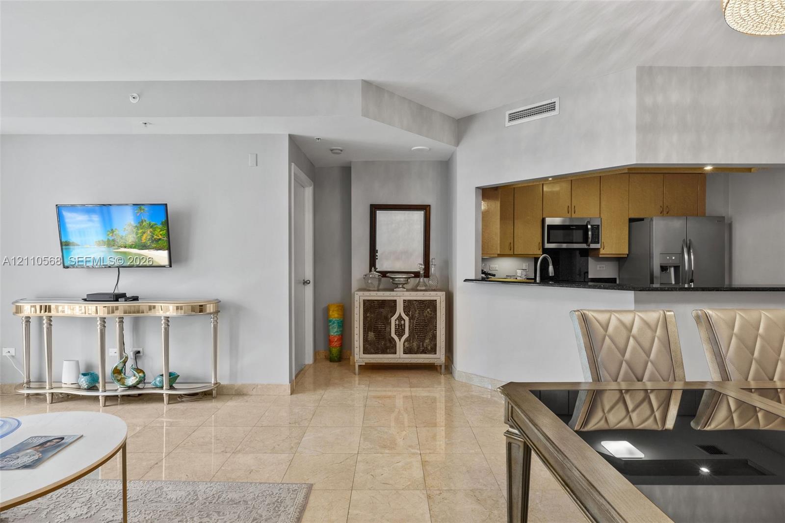 Polished stone flooring, pass-through window to kitchen, neutral wall tones, and built-in stainless steel appliances