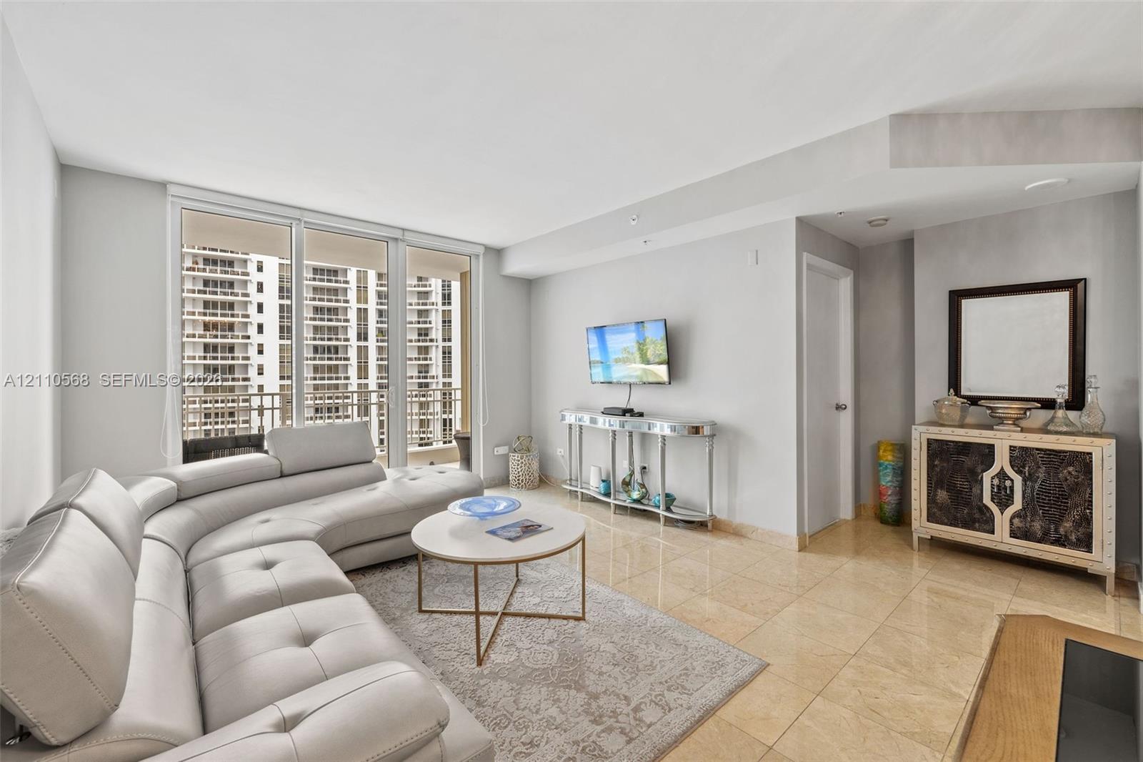 Living area featuring floor-to-ceiling glass sliding doors, stone tile flooring, and neutral wall tones