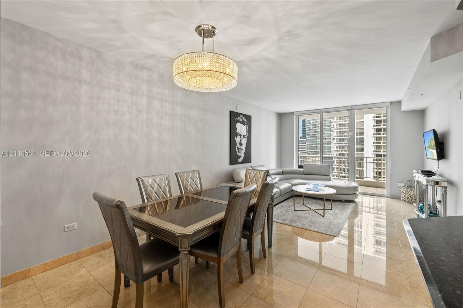 Polished stone flooring, crystalline drum chandelier, and full-height glass balcony doors