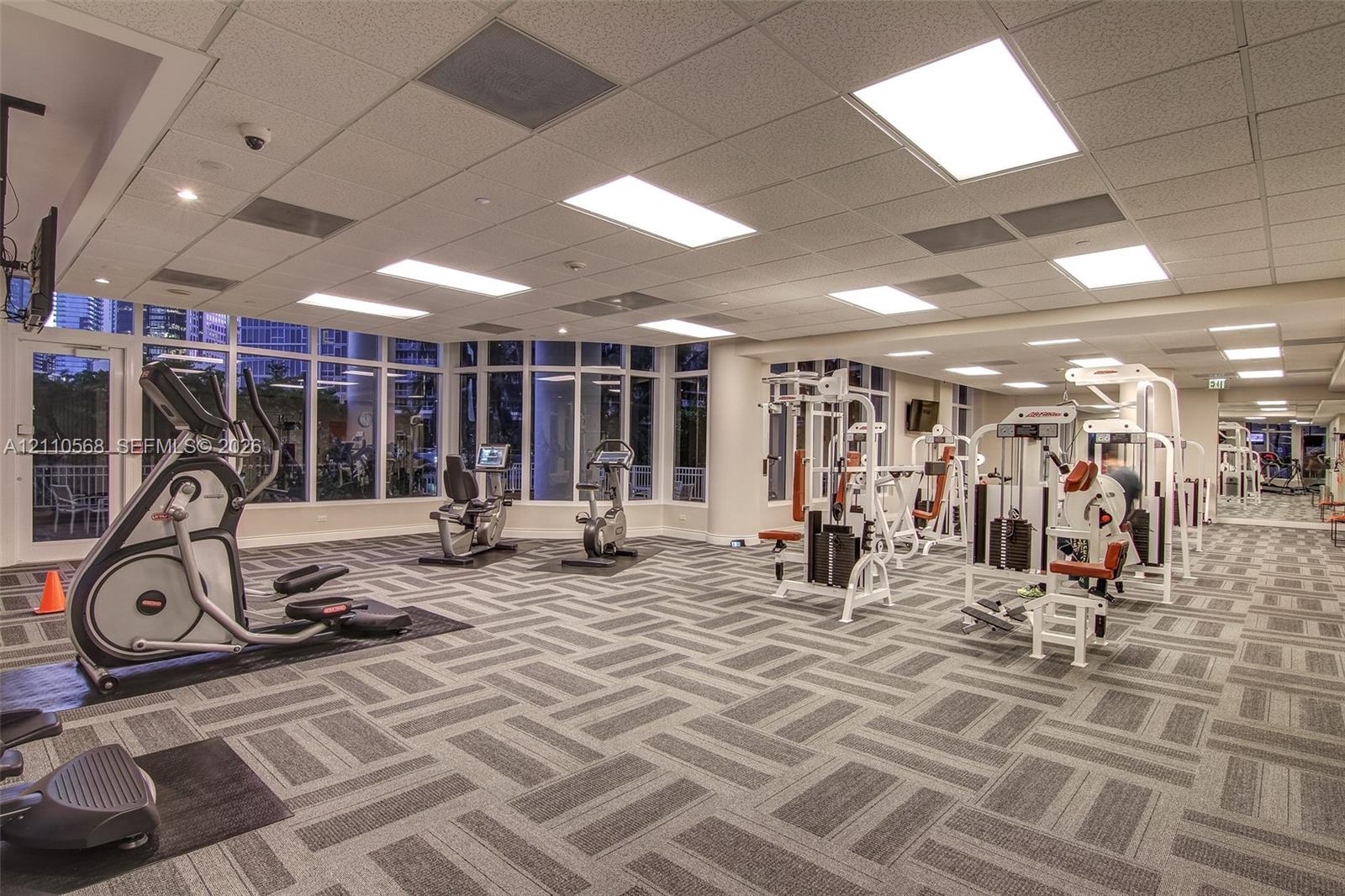 Fitness center featuring floor-to-ceiling windows, patterned carpeting, and recessed ceiling lighting