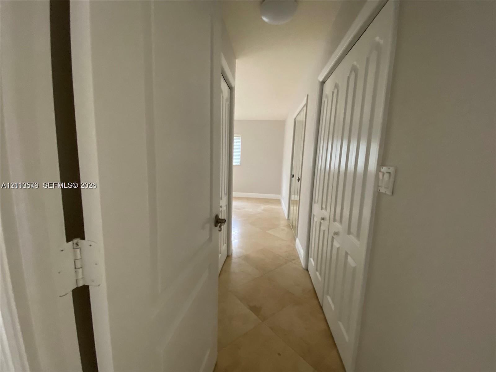 Hallway featuring diagonal tile flooring, multi-panel doors, and built-in closet cabinetry