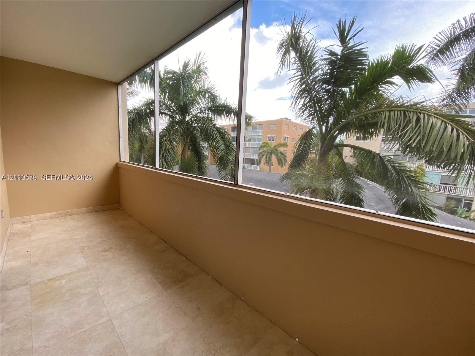 Enclosed balcony featuring light-toned tile flooring, solid wall construction, and expansive screened window panels