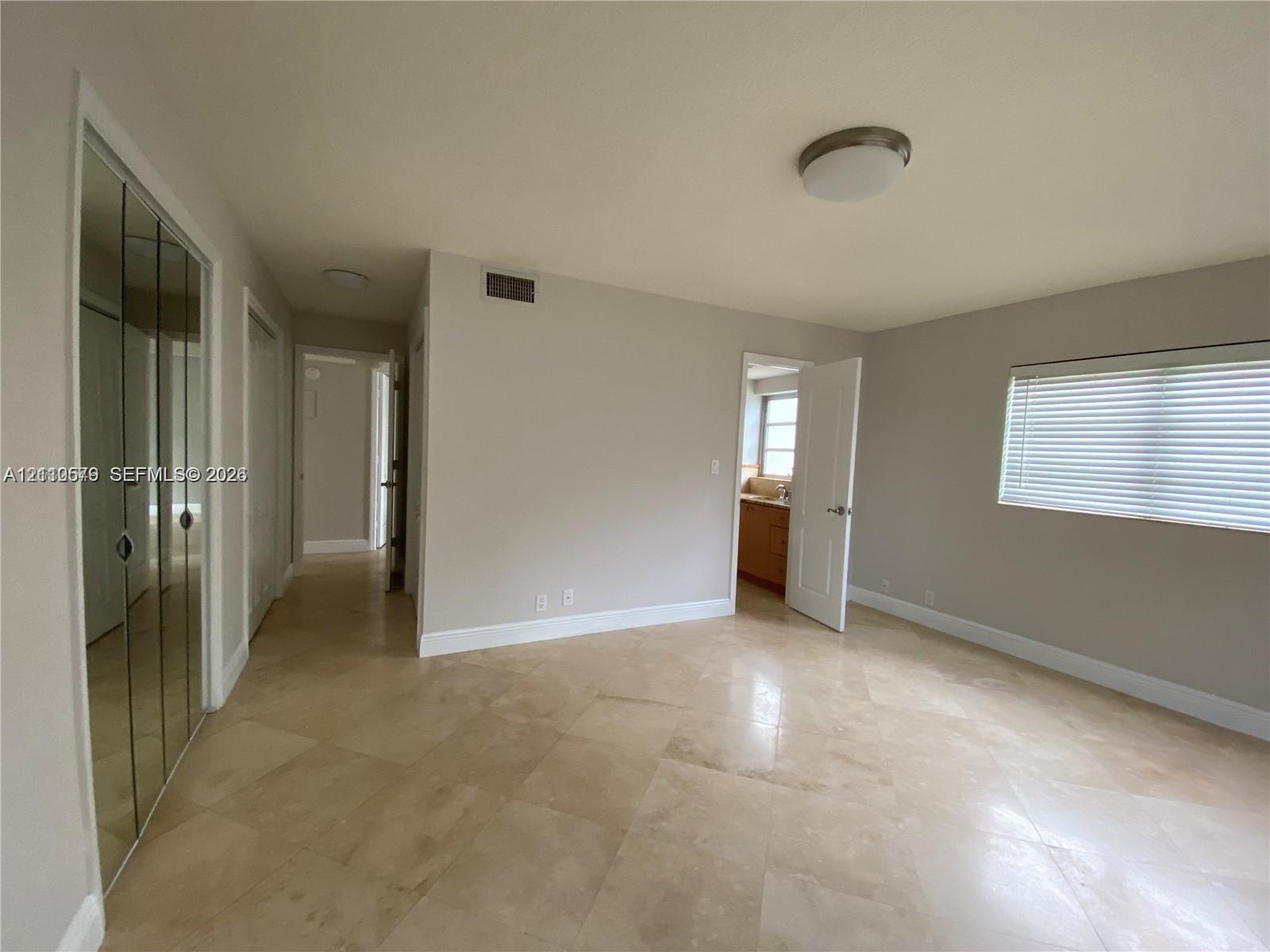 Interior space featuring light-toned stone-finish flooring, floor-to-ceiling mirrored closet doors, and recessed ceiling lighting