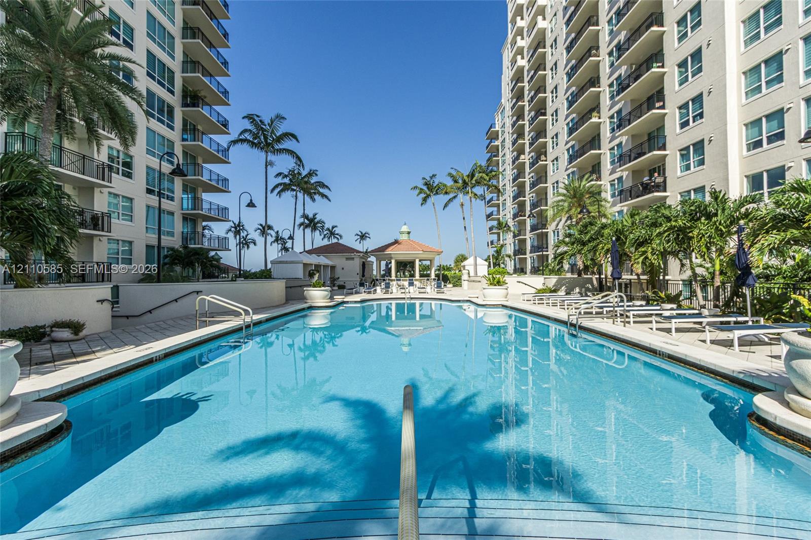 Swimming pool with a paved deck, metal railings, and a central gazebo