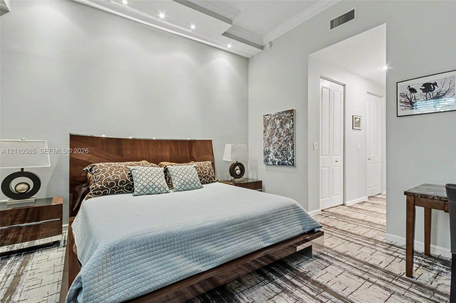 Main Bedroom. Tray ceiling featuring integrated recessed lighting, neutral wall palette, and patterned floor covering