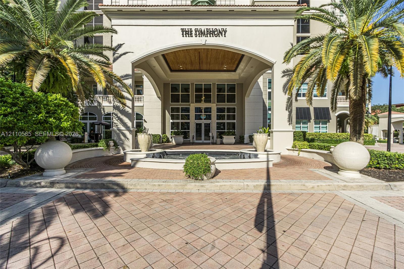 Covered porte-cochre entry featuring a stone-paved motor court, central water fountain, and wood-paneled ceiling detailing