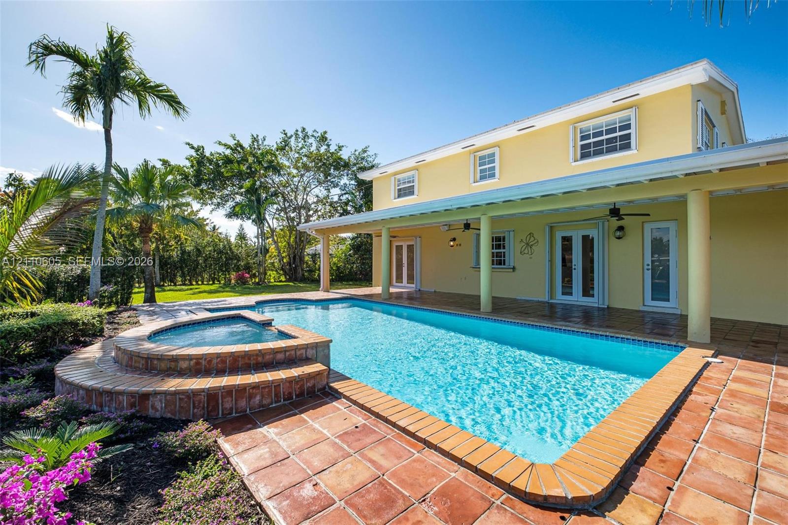 Exterior living area featuring a covered patio, rectangular swimming pool with an integrated spa, and terra-cotta tile decking