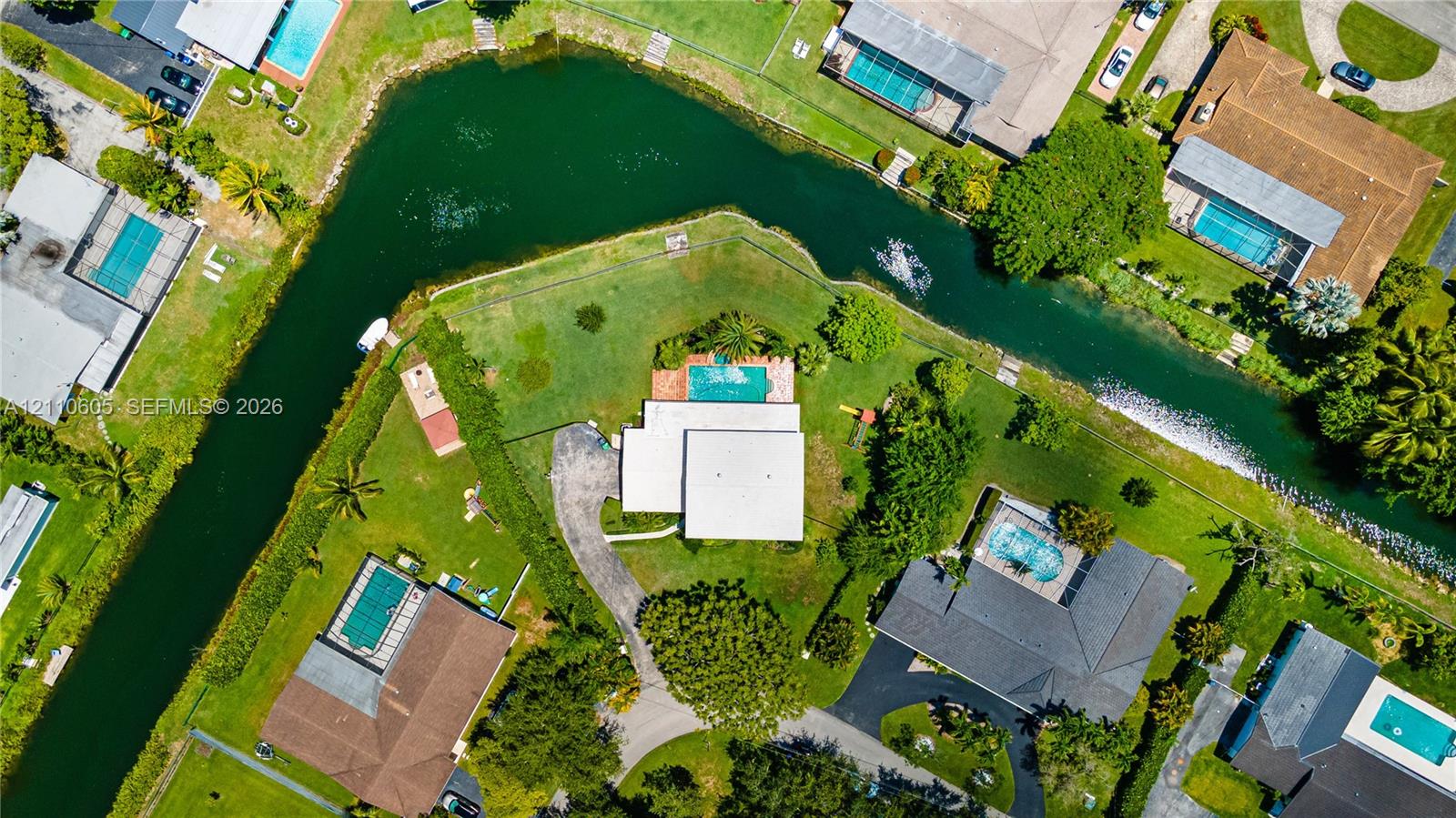 Waterfront parcel featuring a concrete swimming pool, expansive lawn, and direct canal frontage