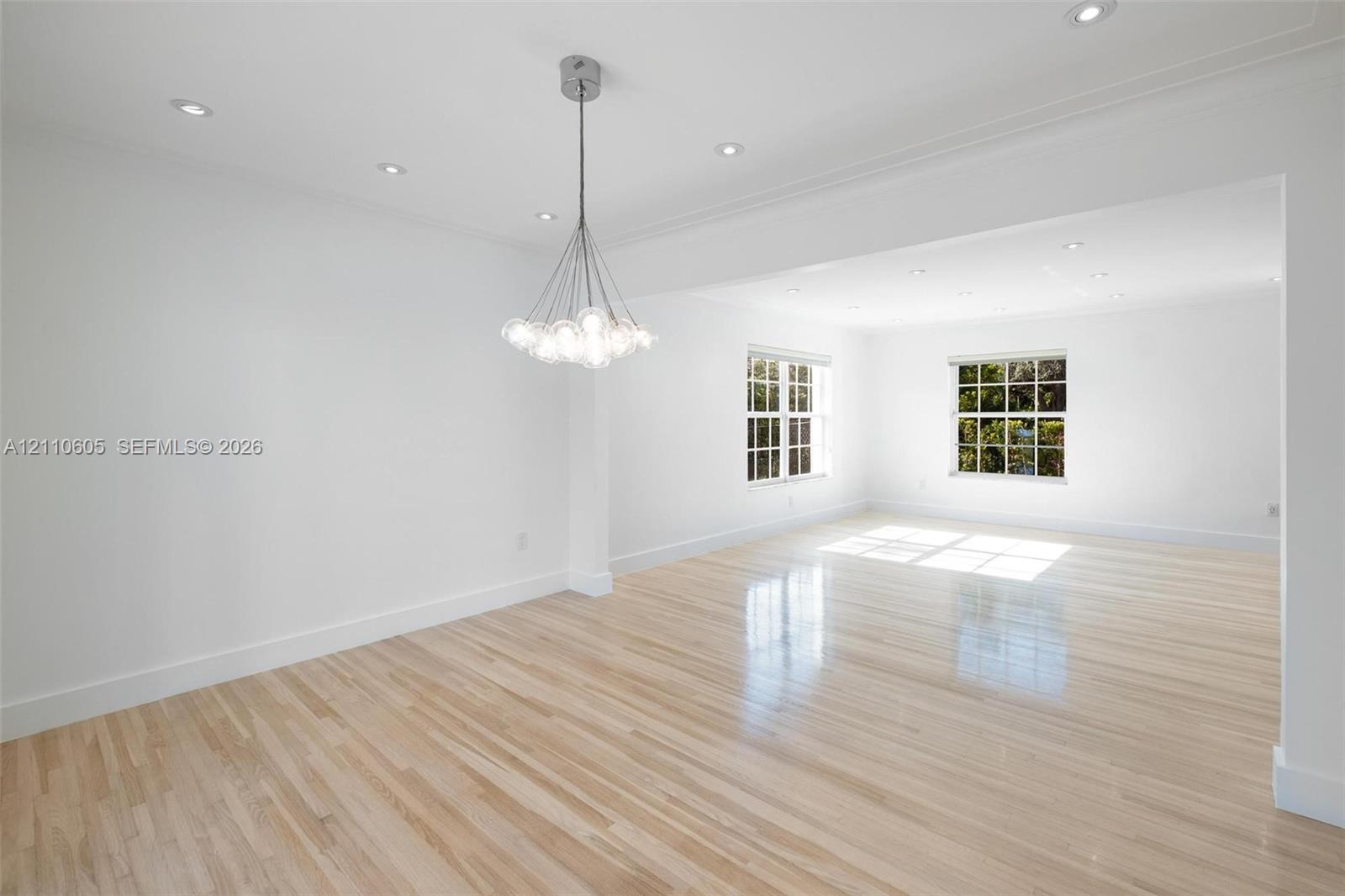 Bright interior featuring wood-finish flooring, multi-pane windows, a contemporary multi-globe pendant light fixture, and recessed lighting