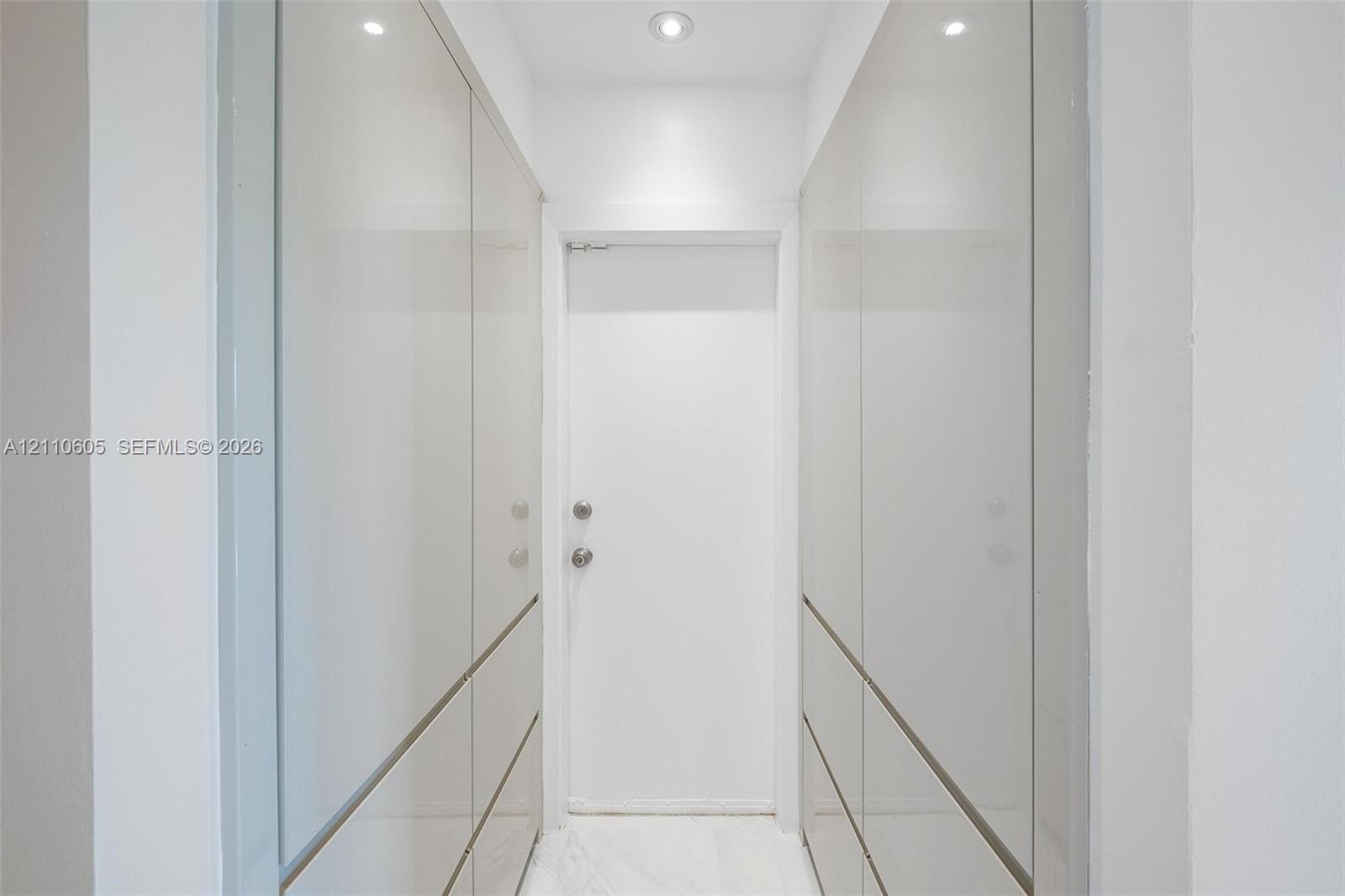 Floor-to-ceiling high-gloss cabinetry with integrated hardware, recessed ceiling lighting, and stone-finish flooring