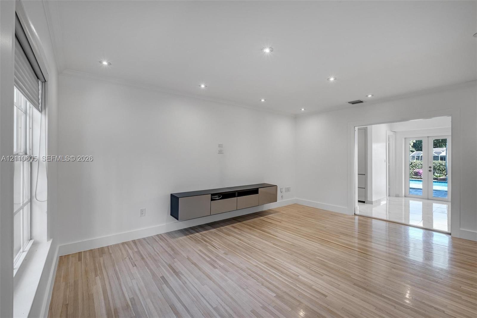 Wood-finish flooring, wall-mounted cabinetry, recessed lighting, and white trim