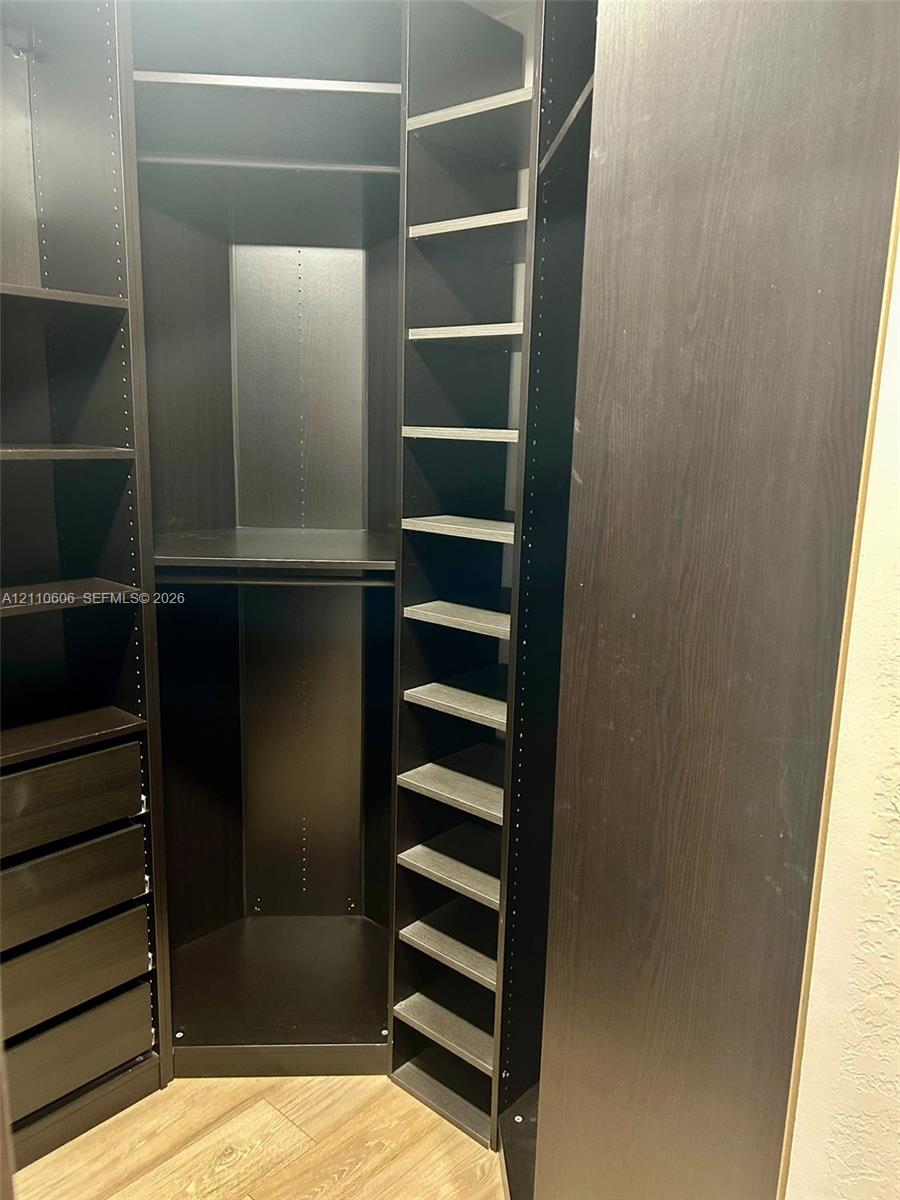 Custom built-in closet organization system featuring dark wood-finish cabinetry, floor-to-ceiling adjustable shelving, multi-tiered hanging rods, and integrated soft-close drawer storage