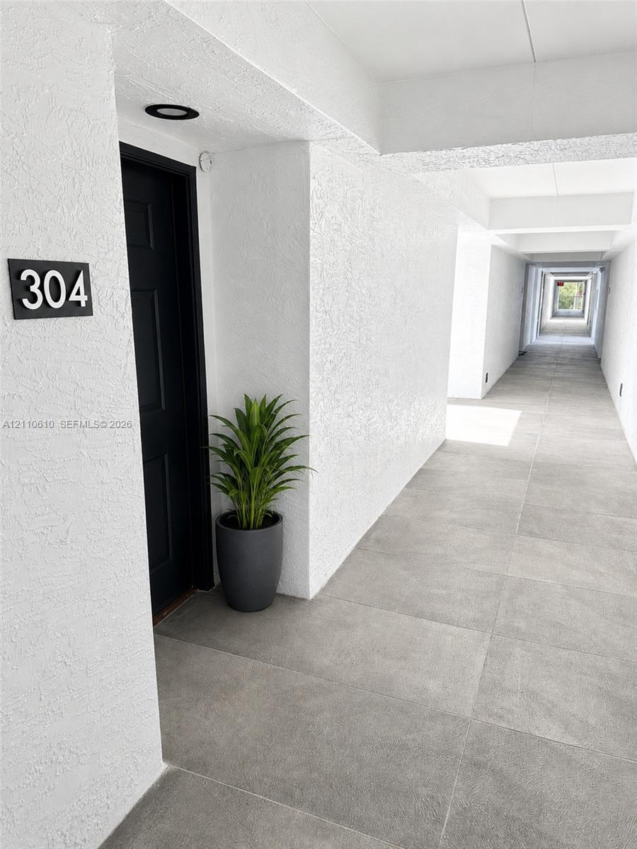 Entryway featuring a solid dark-toned door, textured white wall finishes, large-format grey tile flooring, and recessed ceiling lighting