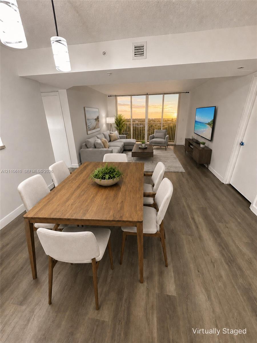 Open-concept floor plan featuring wood-finish flooring, floor-to-ceiling windows, suspended glass pendant lighting, and a walk-out balcony