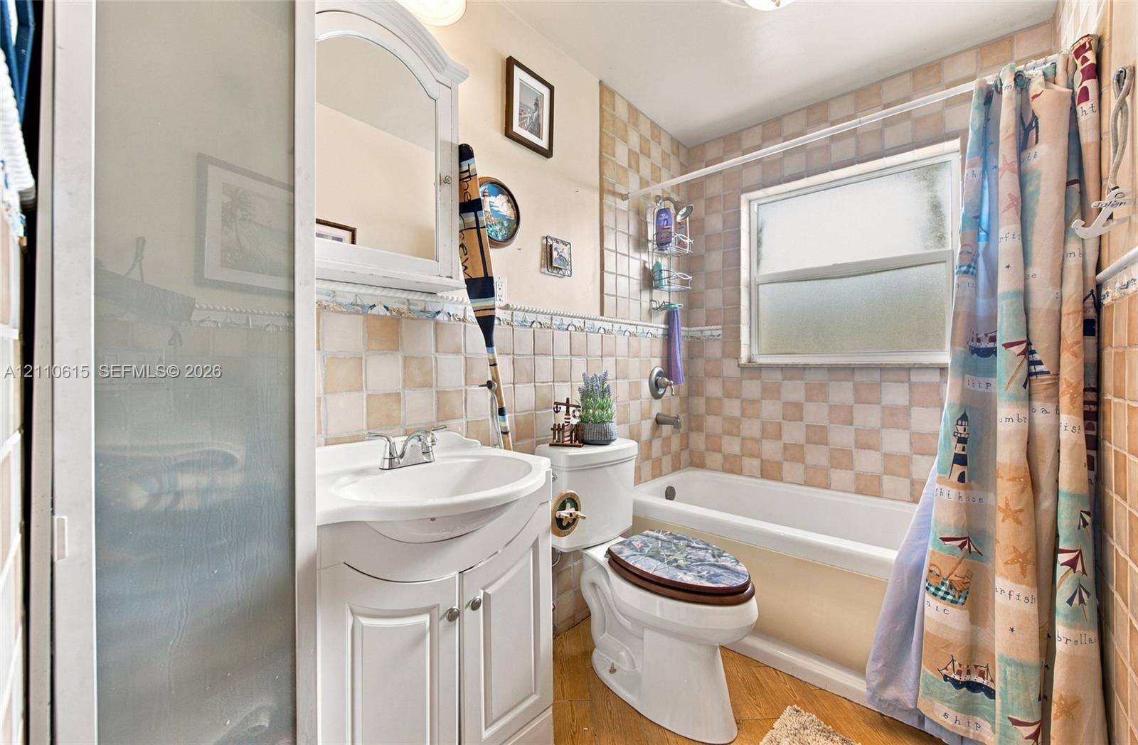 Bathroom featuring a vanity with integrated sink, wall-mounted medicine cabinet, bathtub with shower combination, and tiled wall finishes