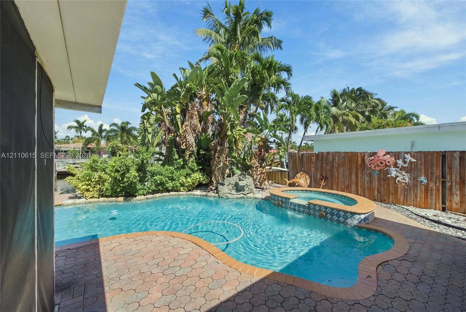 In-ground swimming pool featuring a spillover spa with patterned tile inlay and surround pavers