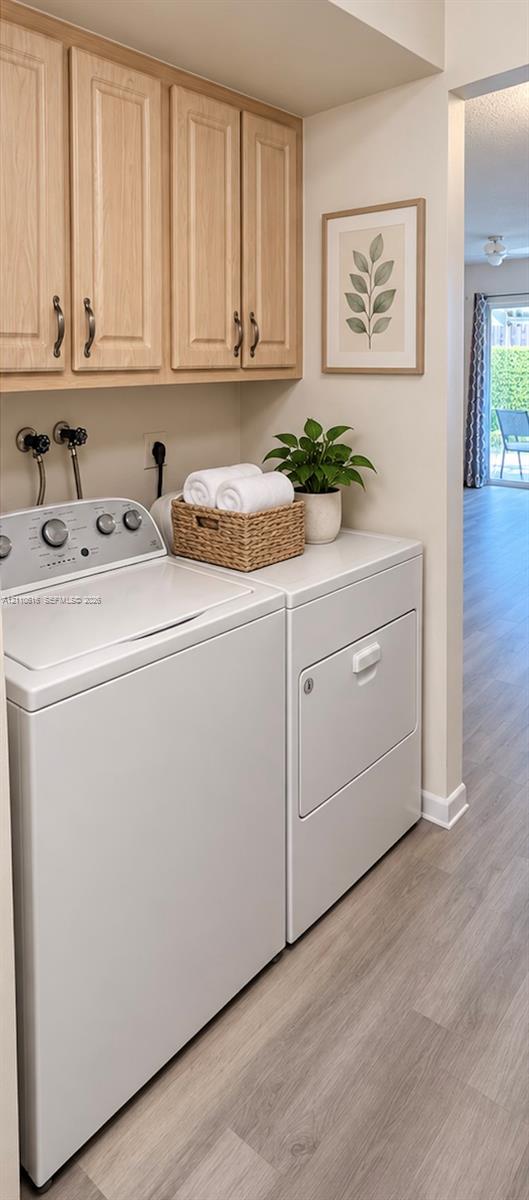 Laundry space featuring light-toned cabinetry, wood-finish flooring, and wall-mounted plumbing hookups Laundry space featuring light-toned cabinetry, wood-finish flooring, and wall-mounted plumbing hookups