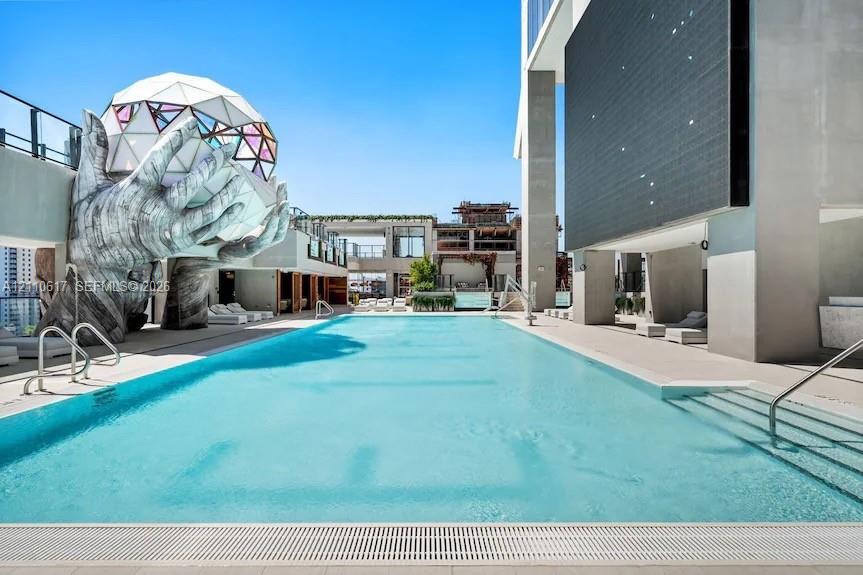 Rooftop swimming pool featuring a geometric dome sculpture, integrated stair entry, tiled surround, and structural pillars
