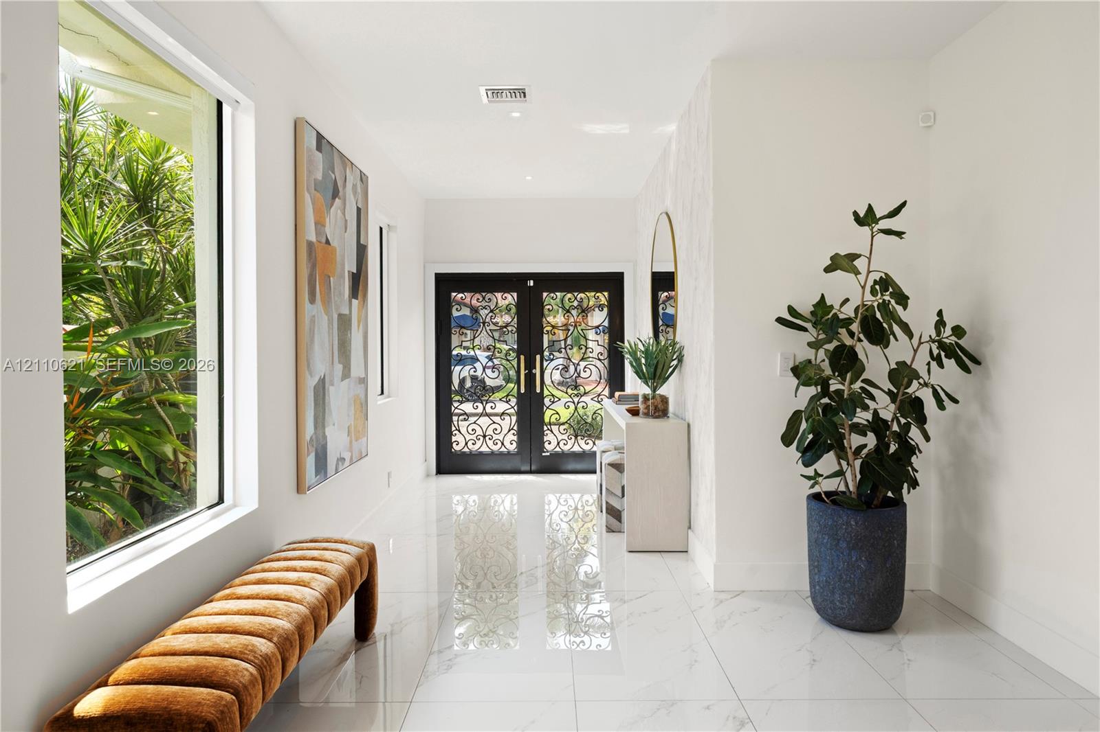 Entryway featuring double doors with ornate metal detailing, large-format stone-finish tile flooring, recessed ceiling lighting, and expansive floor-to-ceiling windows