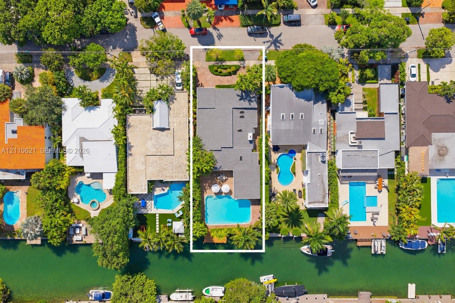 Waterfront property featuring a private swimming pool, paved patio, mature perimeter landscaping, and direct canal access Waterfront property featuring a private swimming pool, paved patio, mature perimeter landscaping, and direct canal access