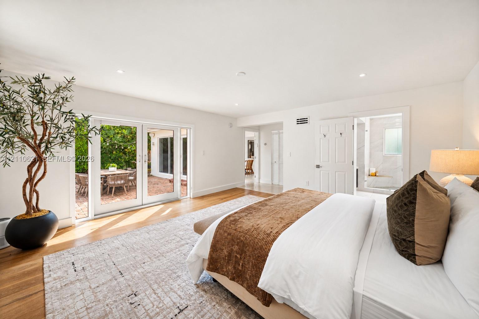 Spacious interior featuring wood-finish flooring, recessed lighting, and white glass-paned double doors opening to an exterior patio