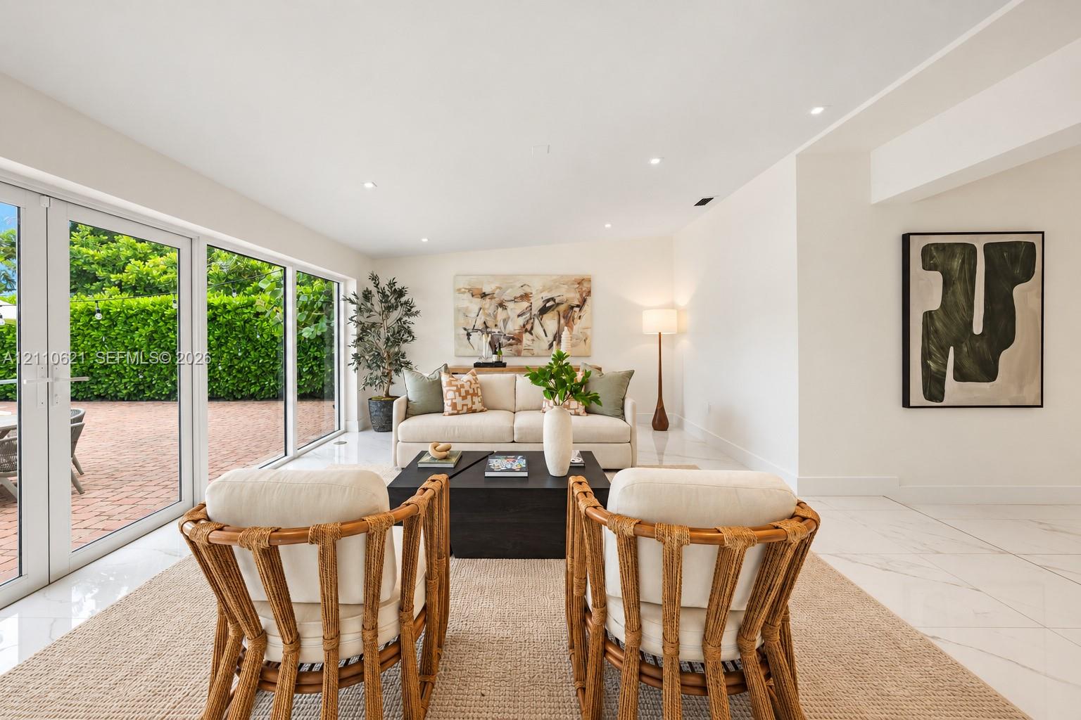 Living space featuring polished light-toned floor tile, white walls, recessed ceiling lighting, and large floor-to-ceiling glass panel doors