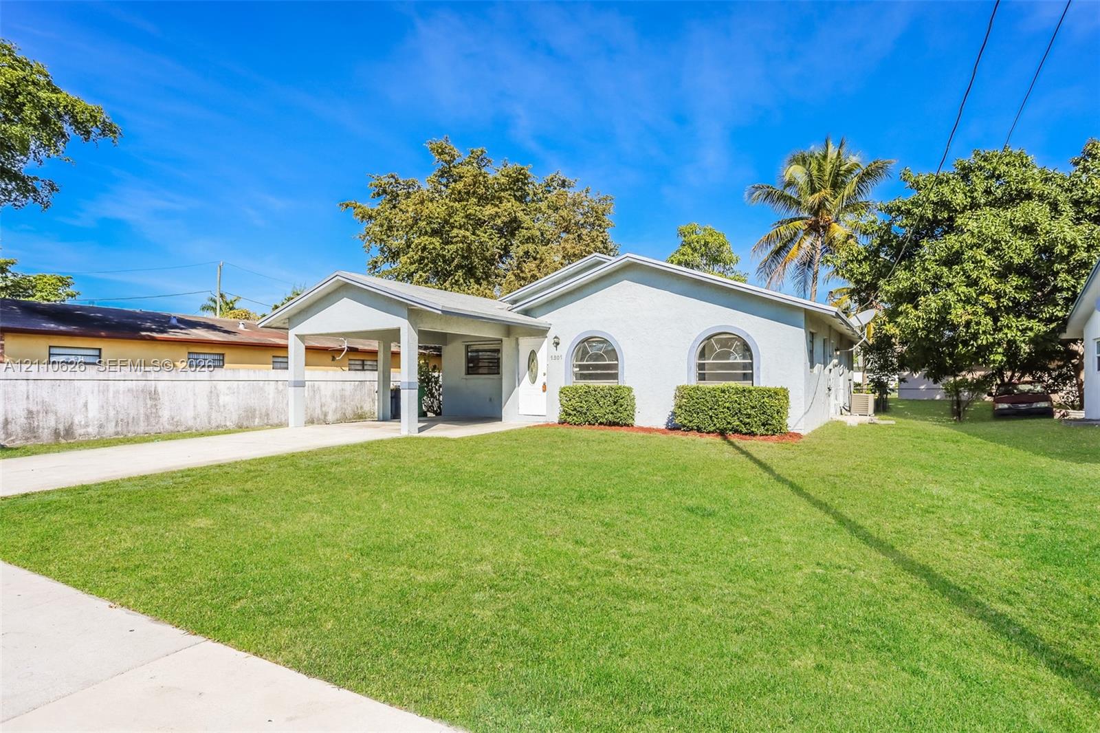 Single-story residence featuring a light-toned stucco exterior, arched front windows, a covered entryway, and a concrete driveway