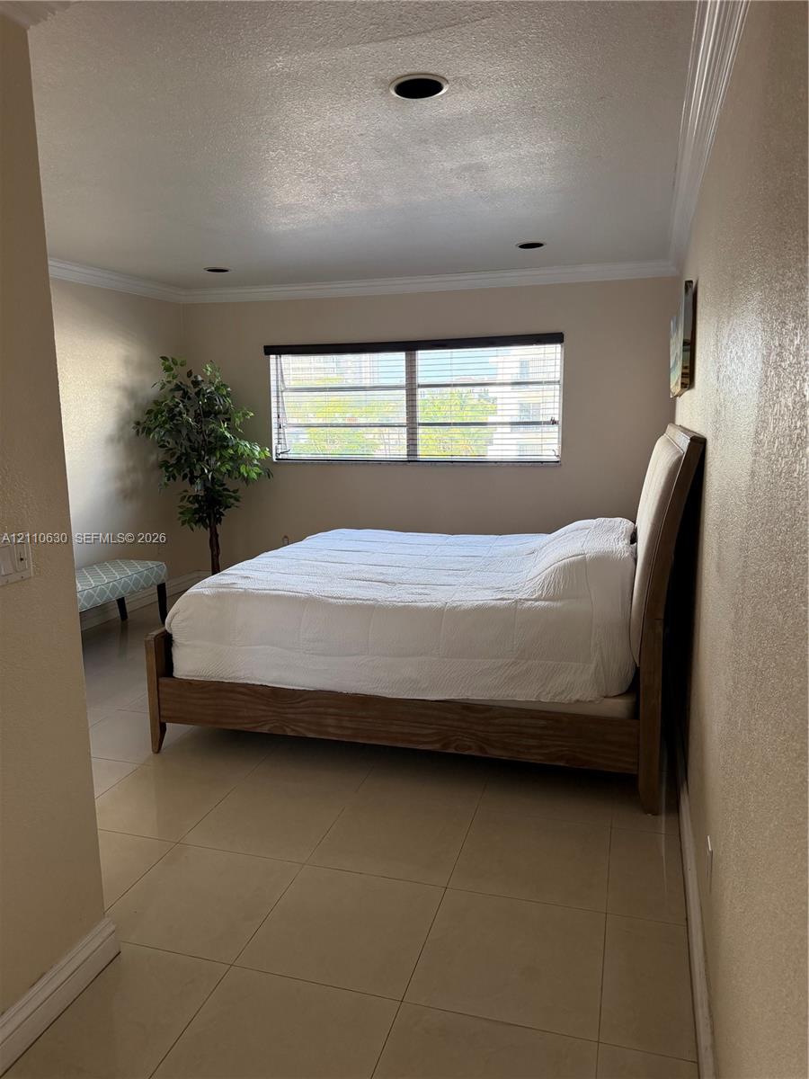 Room featuring neutral-toned walls, crown molding, tile flooring, and recessed lighting