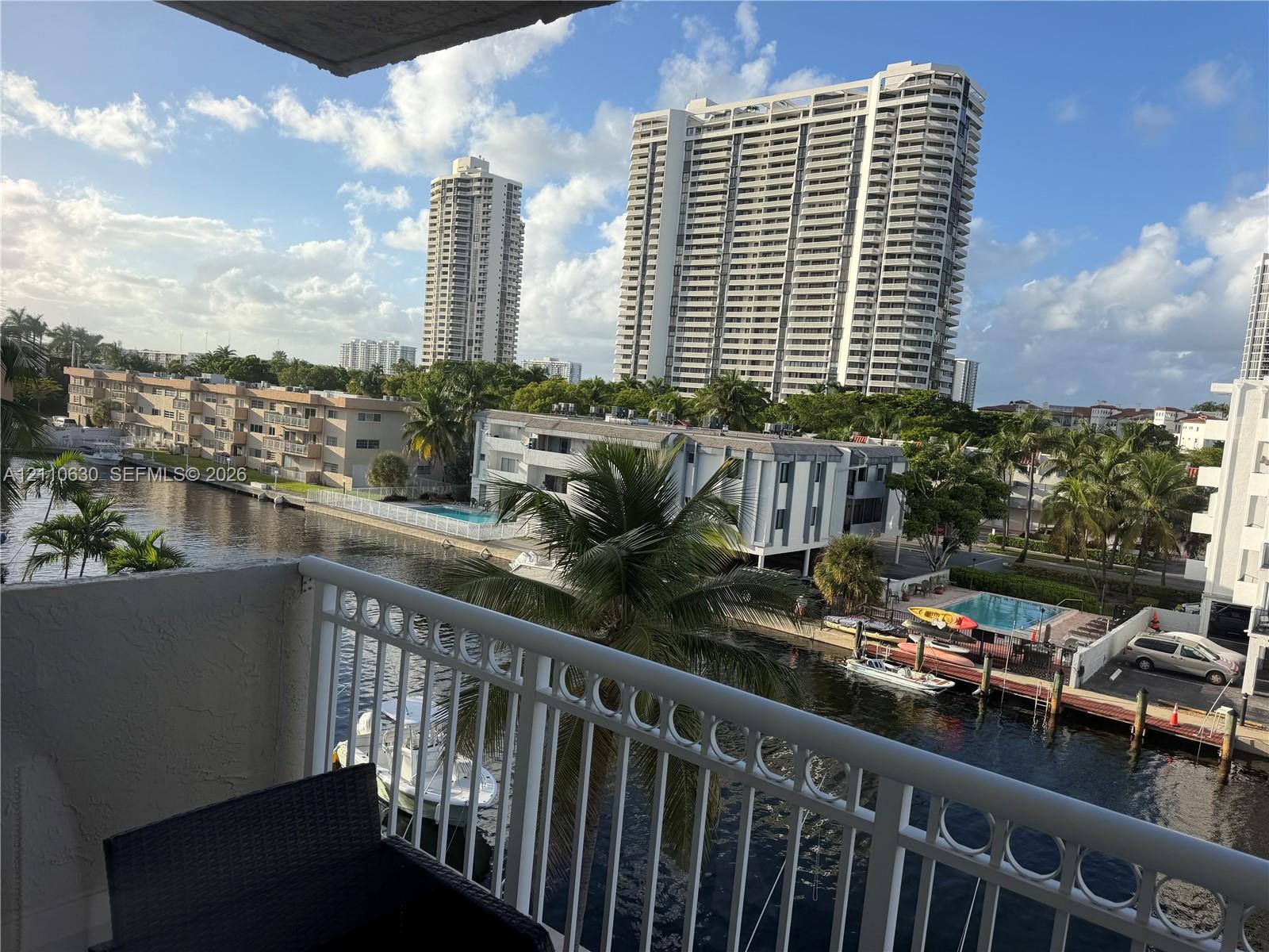 Private balcony with white metal railings overlooking a canal, watercraft, and dense palm tree foliage Private balcony with white metal railings overlooking a canal, watercraft, and dense palm tree foliage