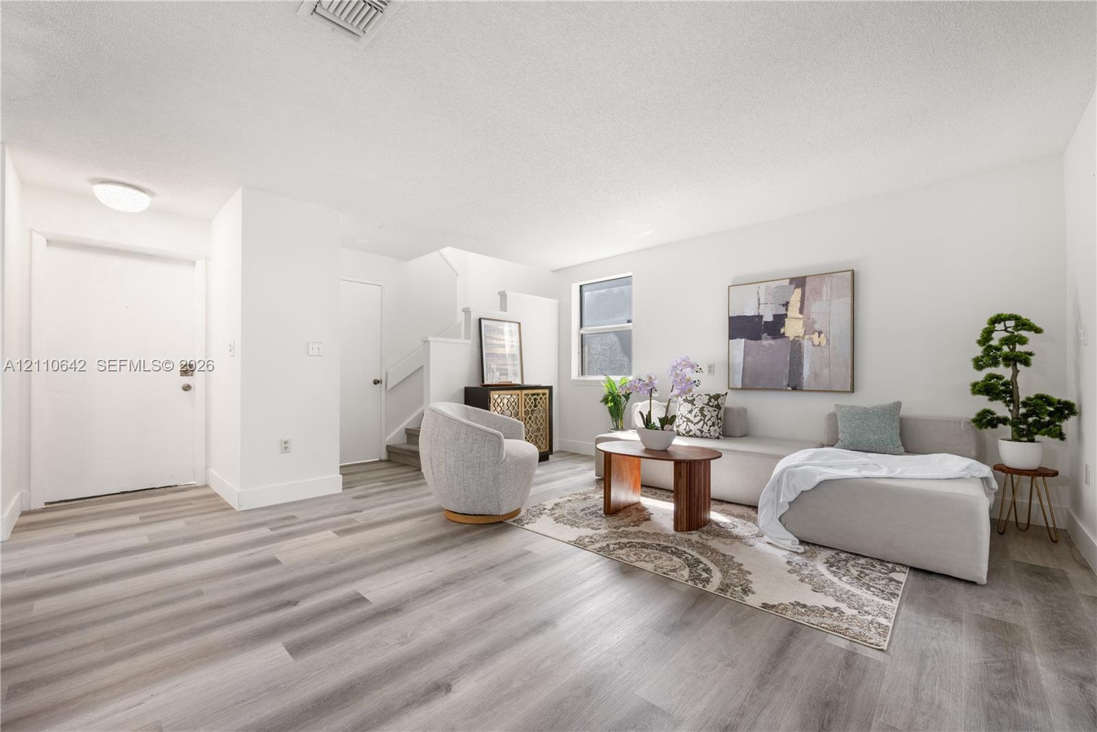 Neutral interior featuring light-toned wood-finish flooring, crisp white wall finishes, and a single-pane window Neutral interior featuring light-toned wood-finish flooring, crisp white wall finishes, and a single-pane window