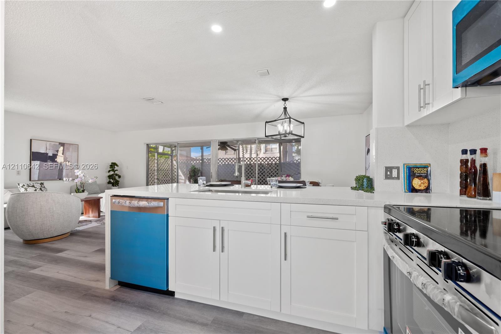 Kitchen featuring white cabinetry, quartz countertops, a stainless steel undermount sink, and wood-finish flooring Kitchen featuring white cabinetry, quartz countertops, a stainless steel undermount sink, and wood-finish flooring