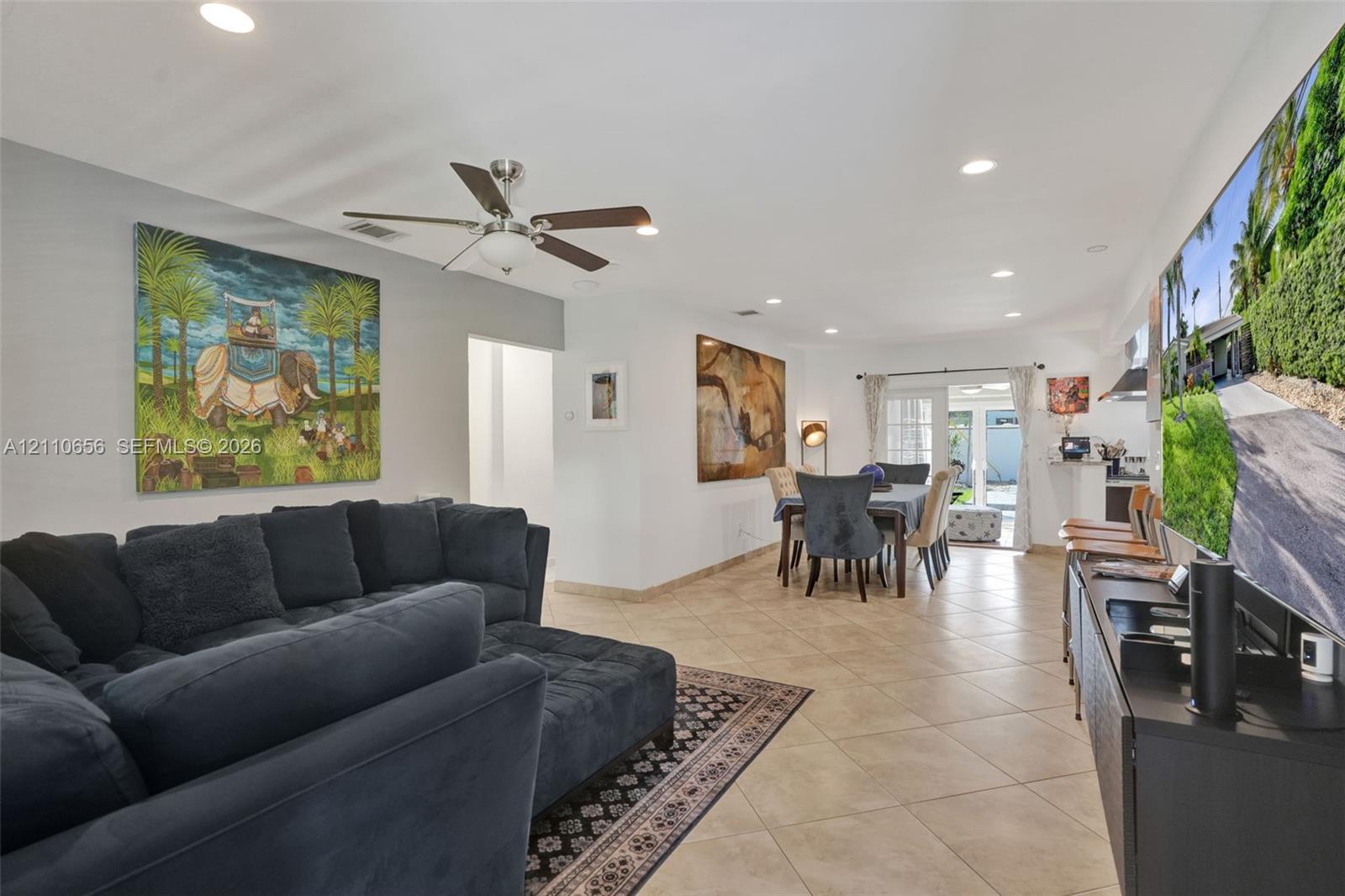 Open-concept interior featuring light-toned tile flooring, recessed ceiling lighting, and a multi-blade ceiling fan