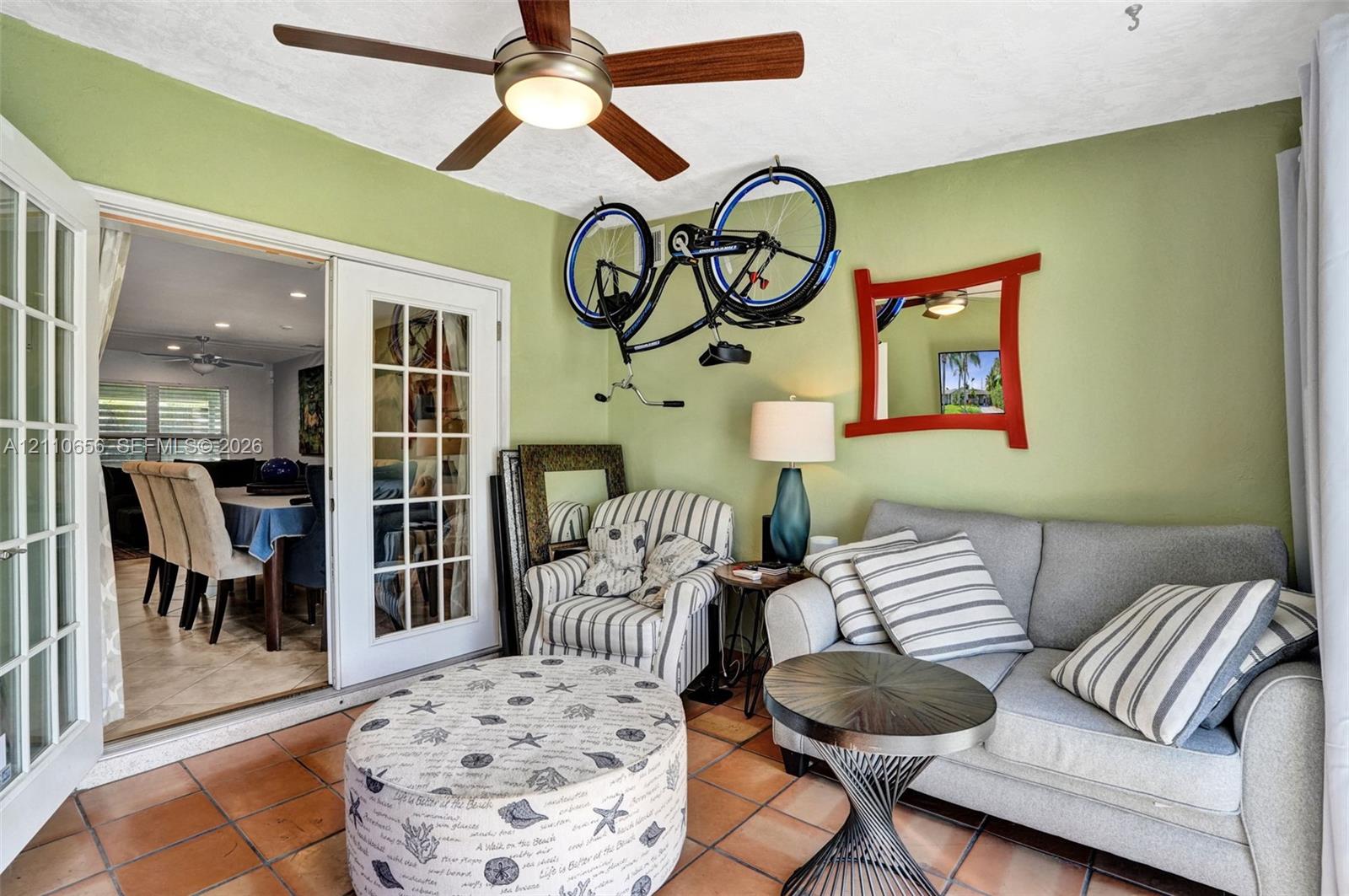 Sunroom featuring tile flooring, French doors with glass panes, and a ceiling-mounted light fixture with a multi-blade fan