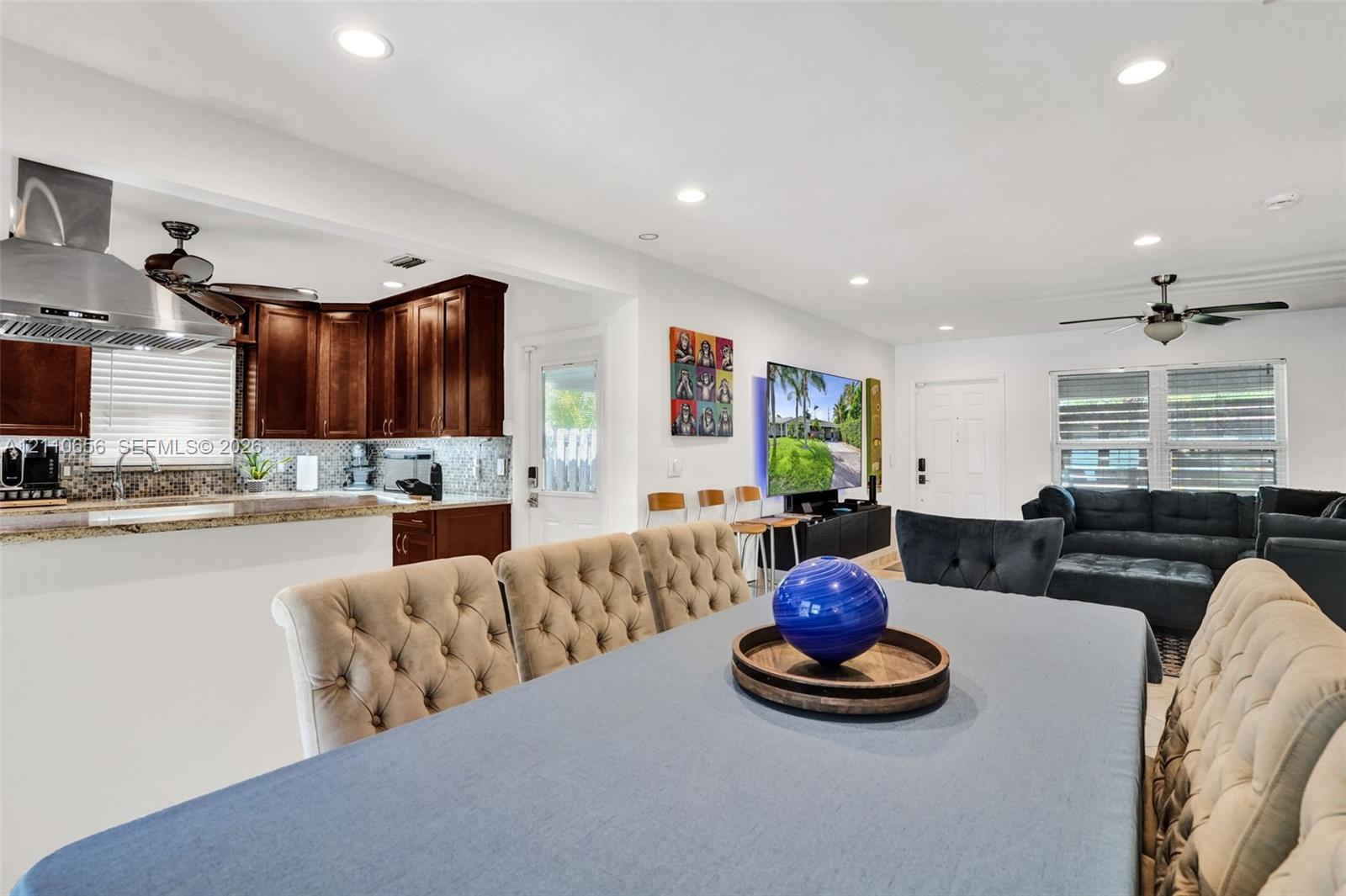 Kitchen featuring dark wood cabinetry, stainless steel range hood, stone countertops, and recessed lighting