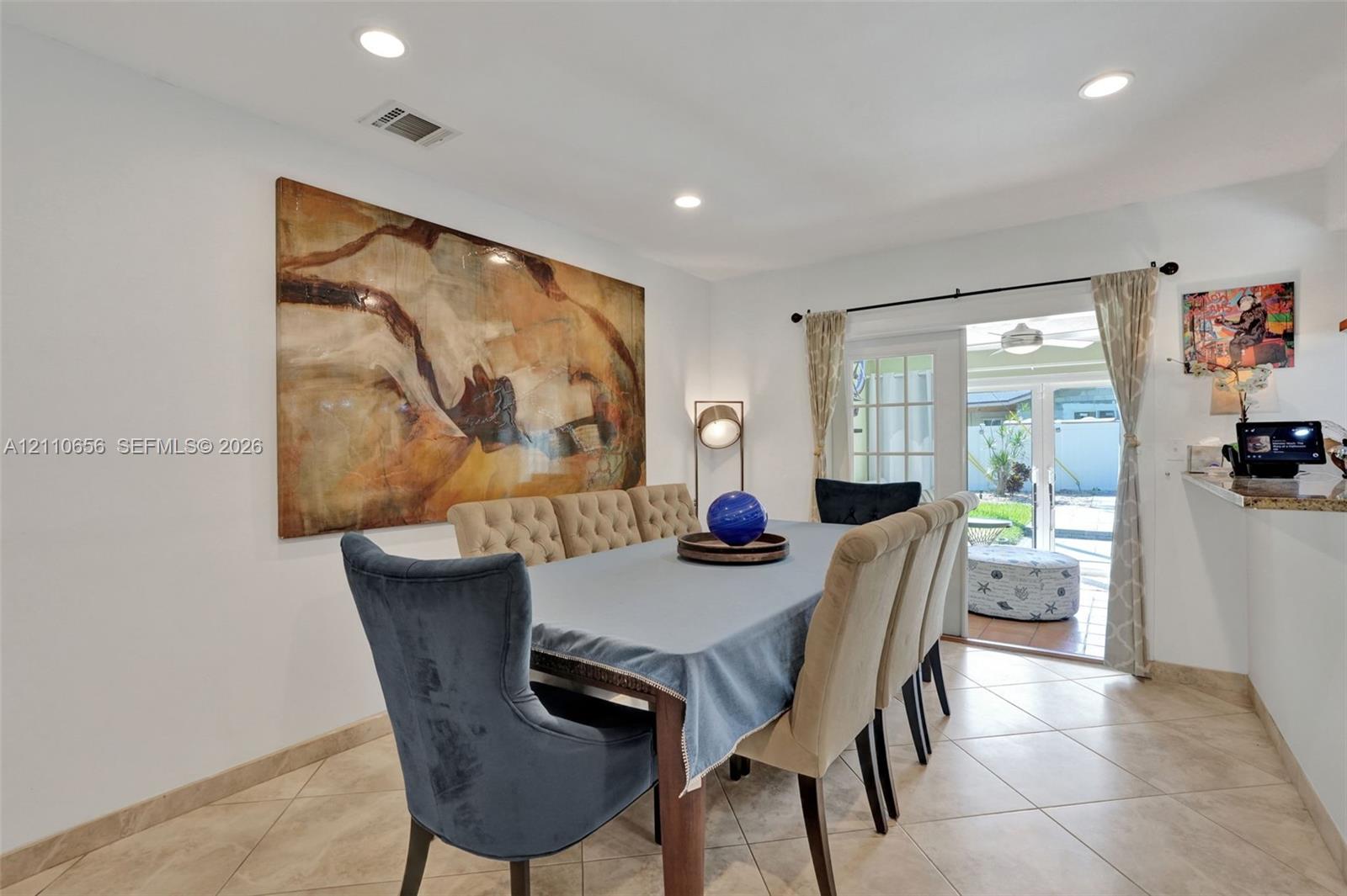 Neutral tile flooring, recessed lighting, and a glass-paneled sliding door providing exterior access