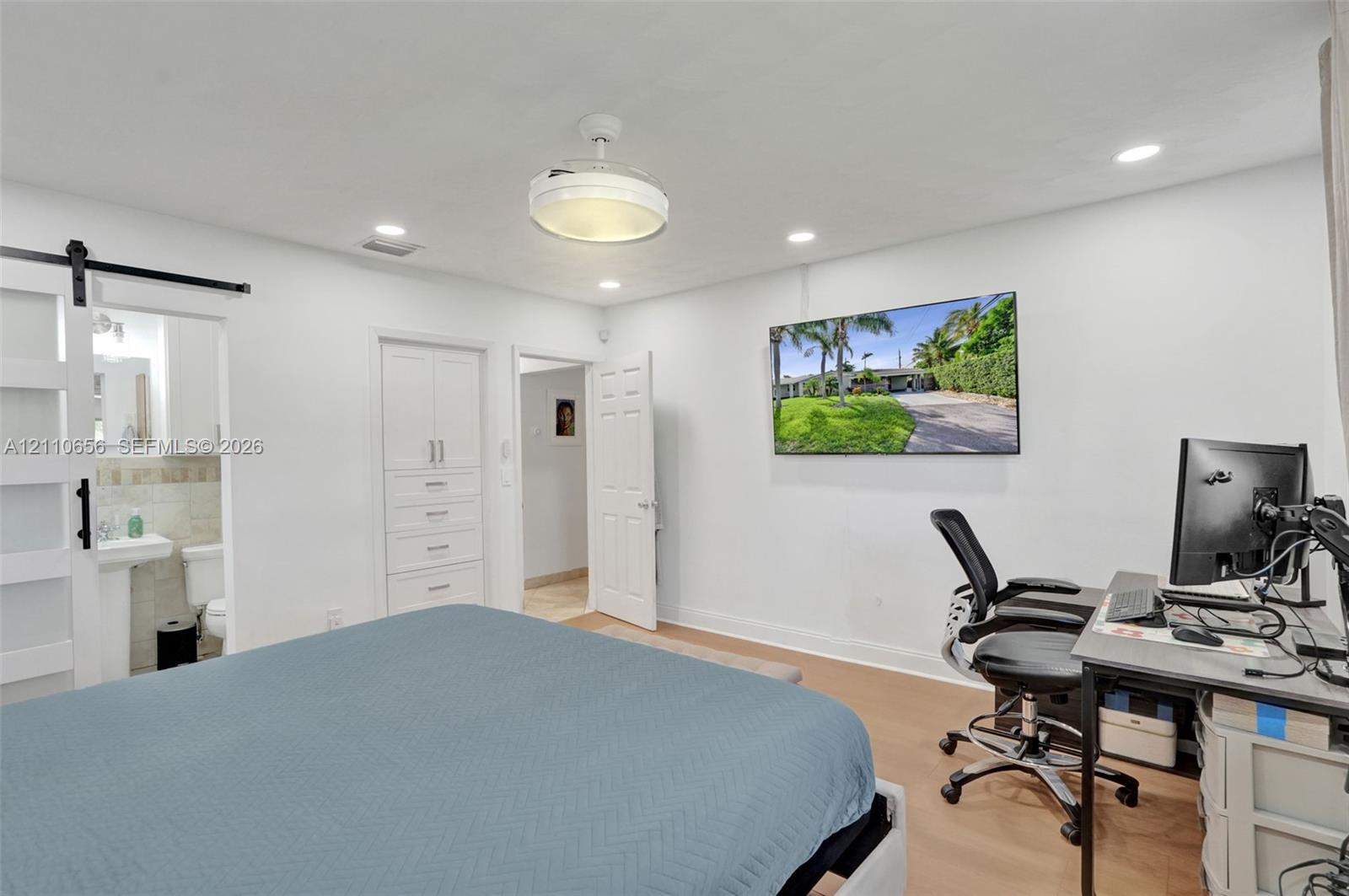 Interior space featuring wood-finish flooring, recessed lighting, a ceiling fan with integrated lighting, built-in cabinetry, and a sliding barn door