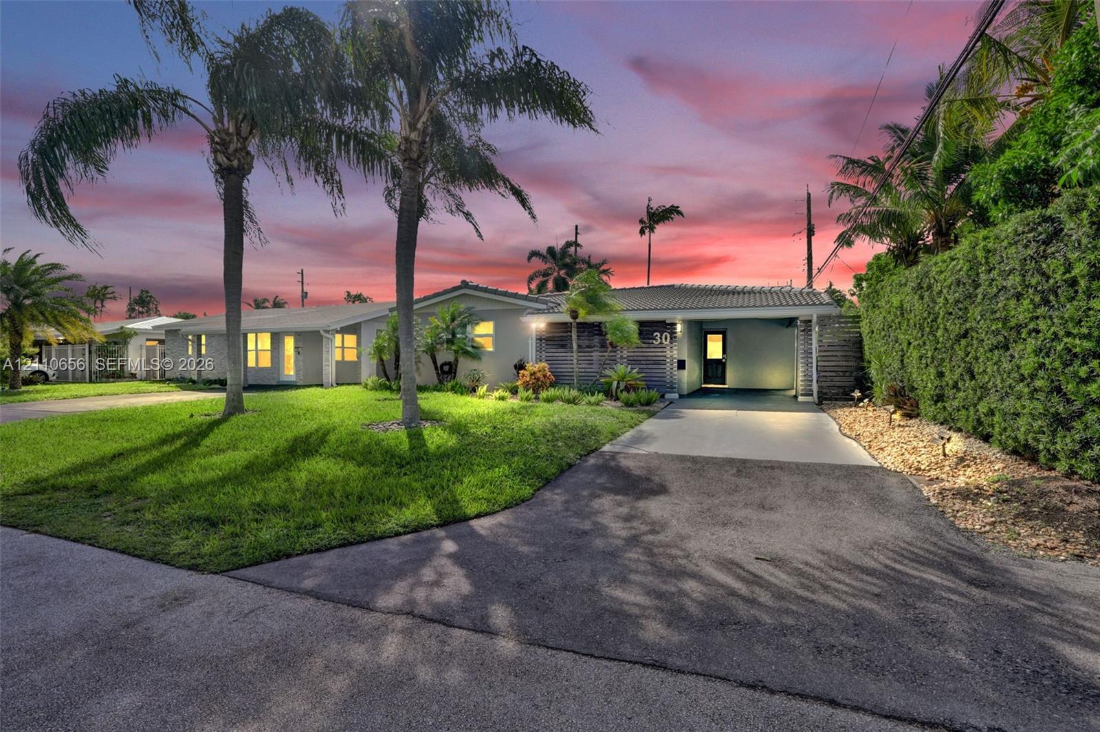 Single-story exterior featuring a concrete tile roof, integrated carport, manicured lawn, and established palm trees Single-story exterior featuring a concrete tile roof, integrated carport, manicured lawn, and established palm trees