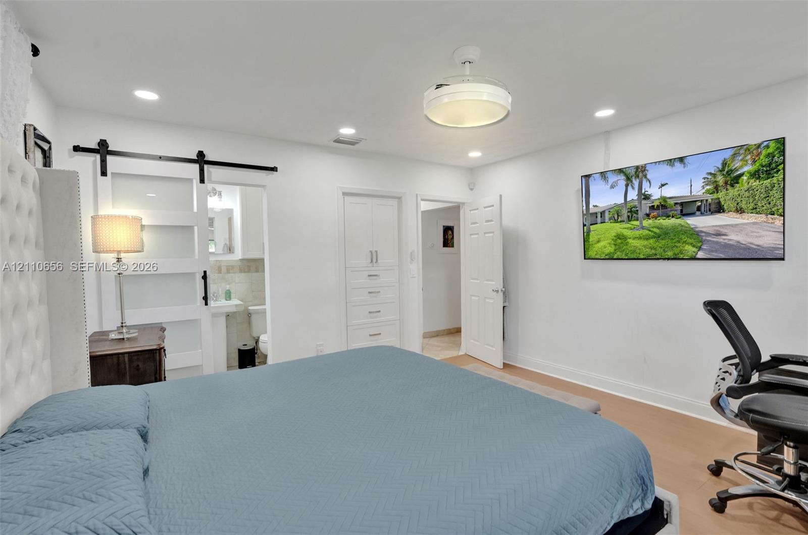 Interior featuring recessed lighting, a ceiling-mounted drum light fixture, sliding frosted-glass barn door with matte black hardware, and built-in floor-to-ceiling cabinetry