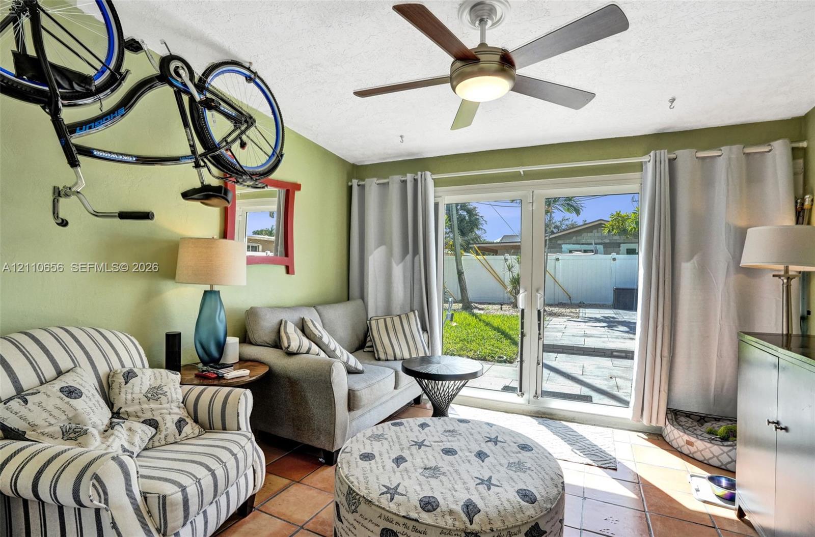 Sliding glass patio doors, neutral tile flooring, and a modern ceiling fan with integrated lighting