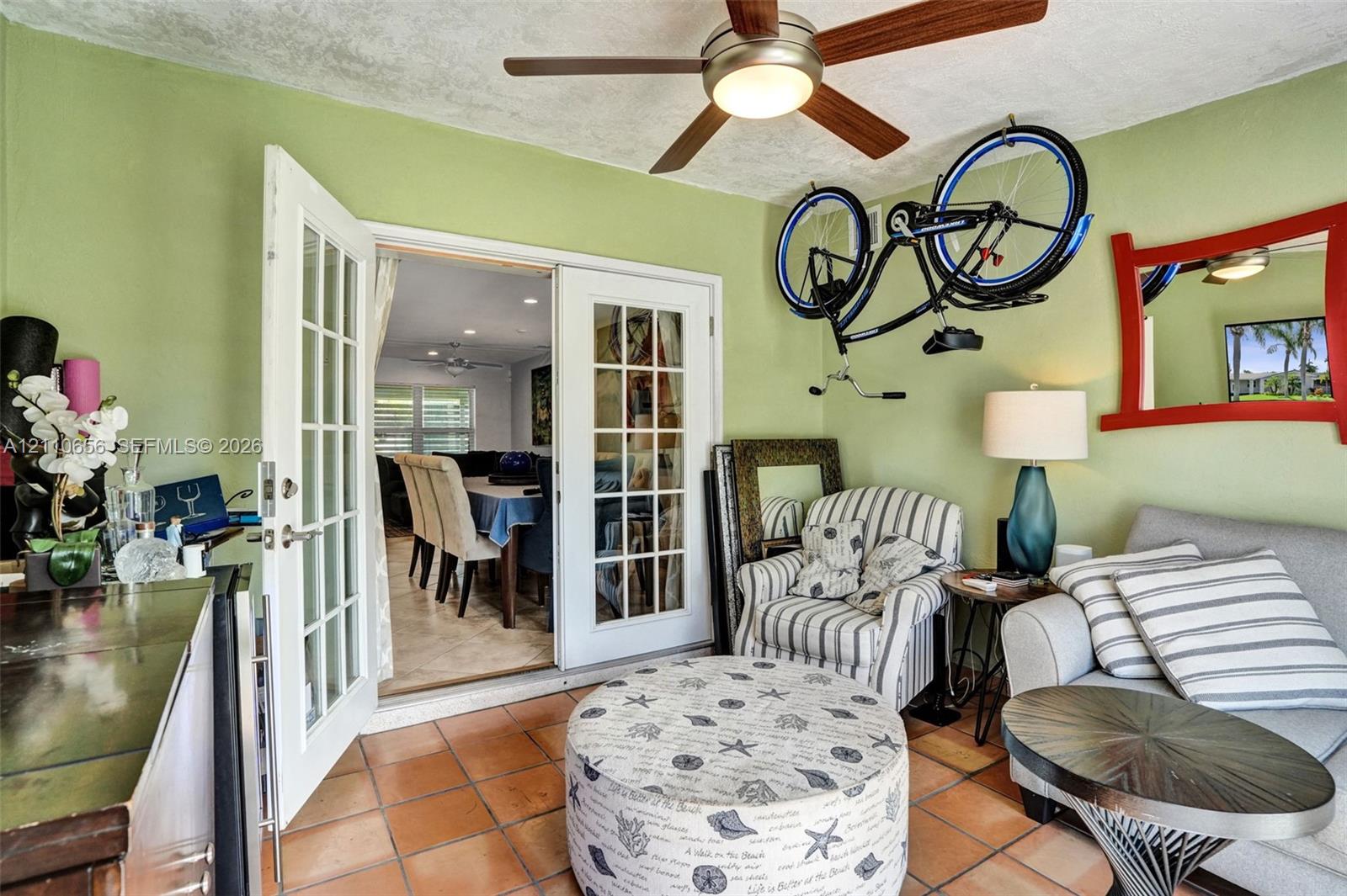 Multi-lite glass French doors with white frames, tile flooring, and a ceiling-mounted light fixture with fan