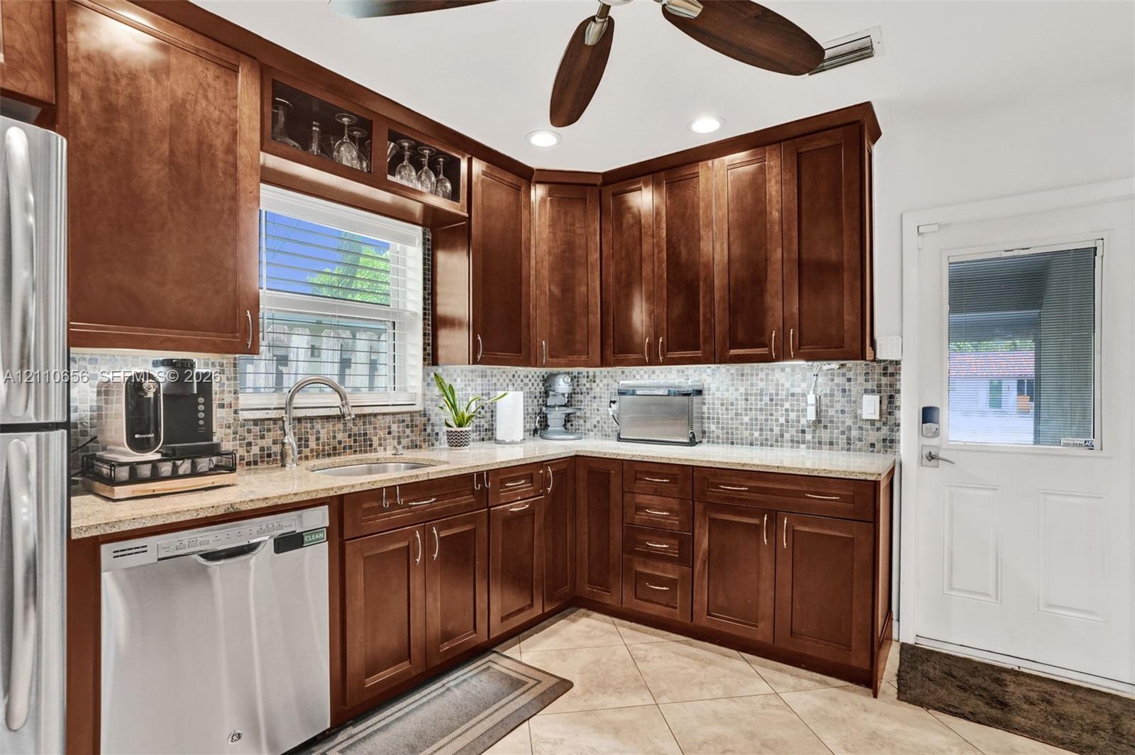 Kitchen featuring raised-panel wood cabinetry, mosaic tile backsplash, solid-surface countertops, recessed lighting, and tile flooring