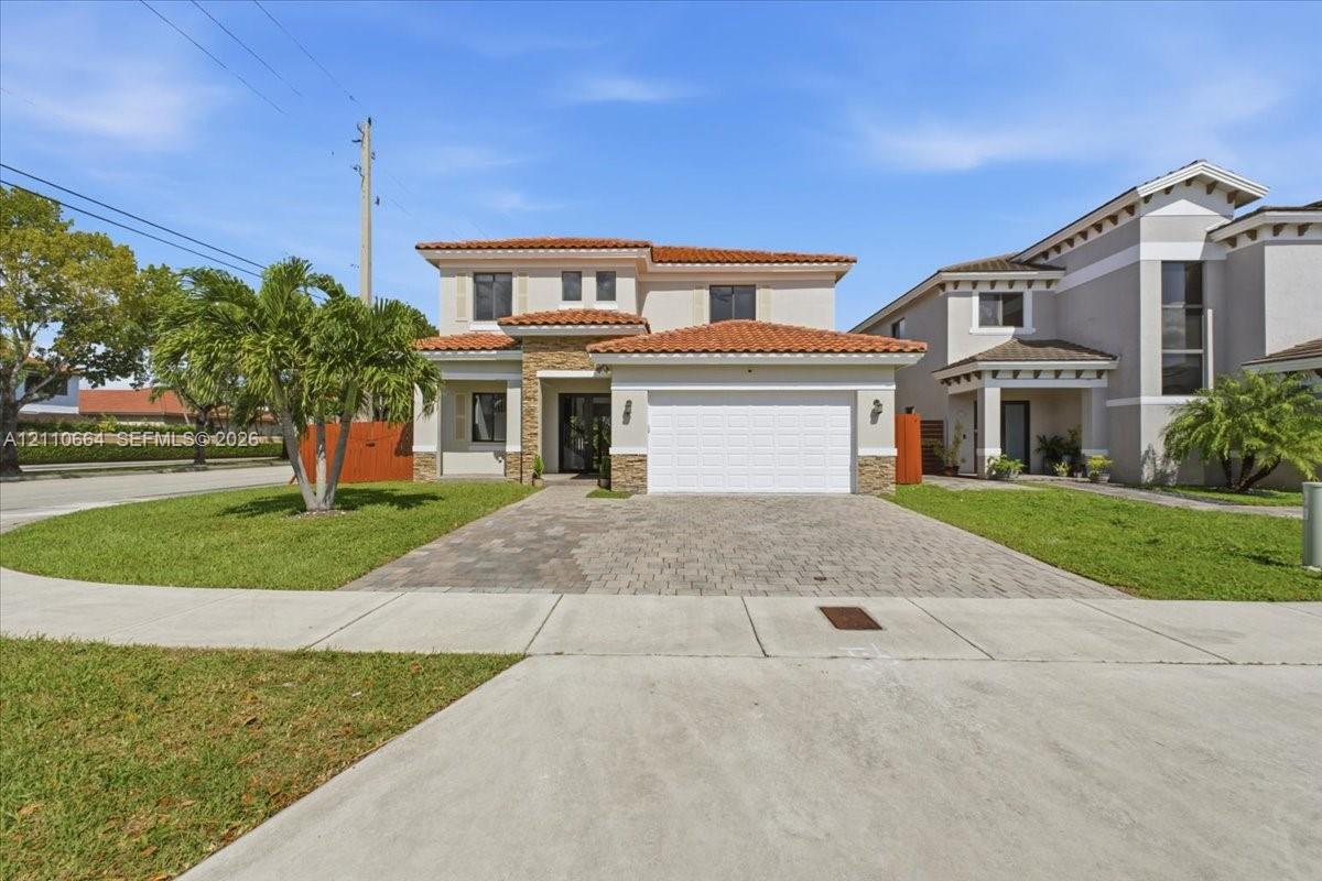 Two-story residence featuring a tile roof, exterior stone veneer accents, a paver driveway and an attached two-car garage Two-story residence featuring a tile roof, exterior stone veneer accents, a paver driveway and an attached two-car garage