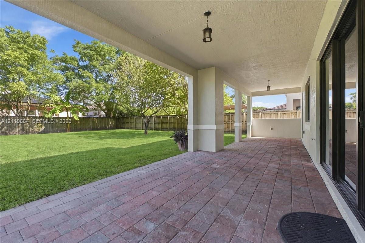 Spacious covered patio with paver flooring, opening to a fully fenced backyard with ample room for a custom pool and an expansive outdoor entertaining retreat