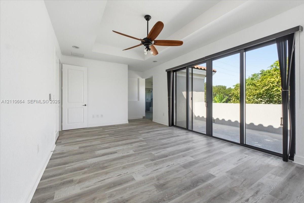An elegant tray ceiling adds architectural distinction, while expansive multi-panel glass doors fill the space with natural light, providing access to a private balcony