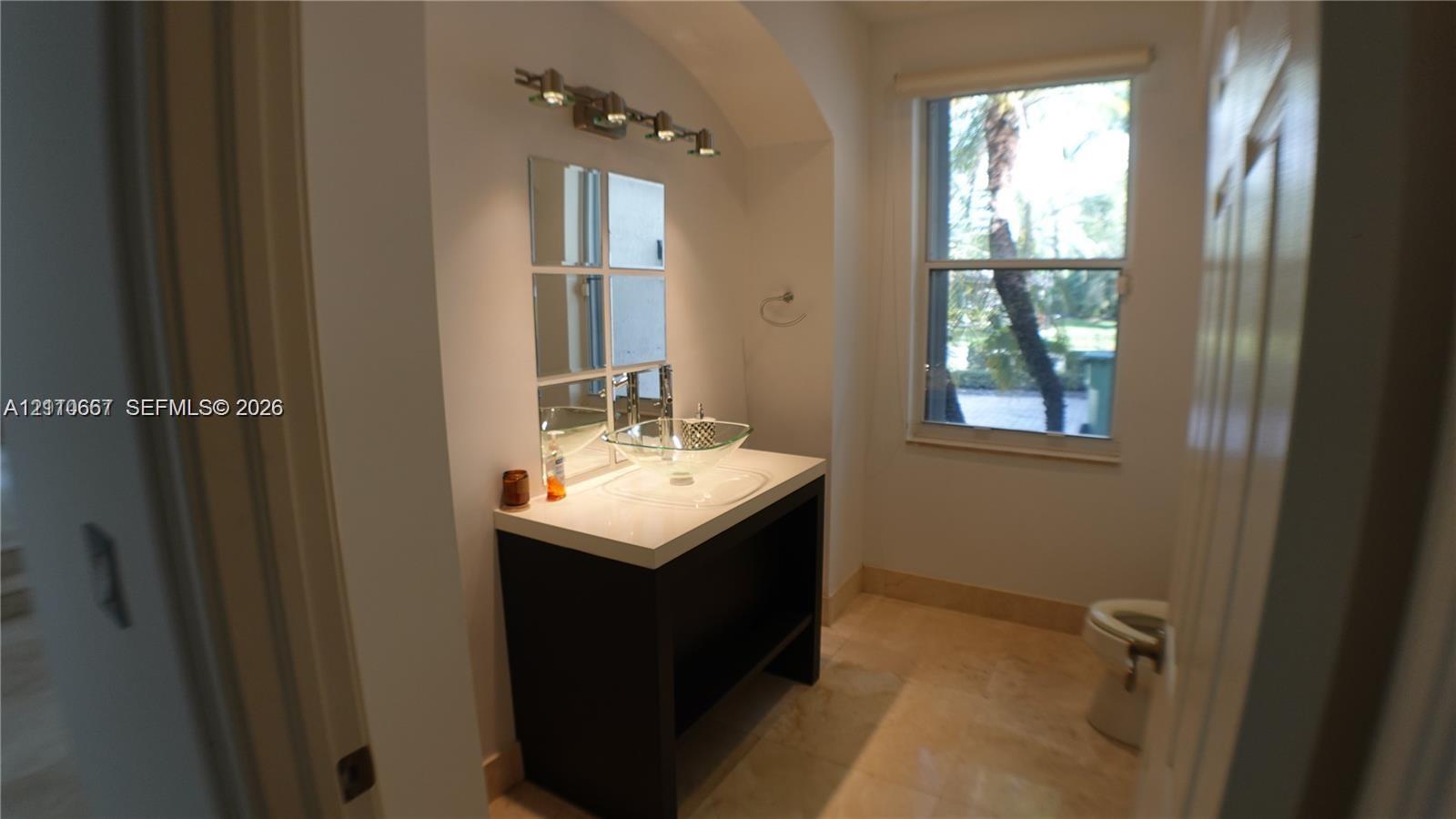 Room featuring a tray ceiling, arched entryway, and dark wood-finish flooring