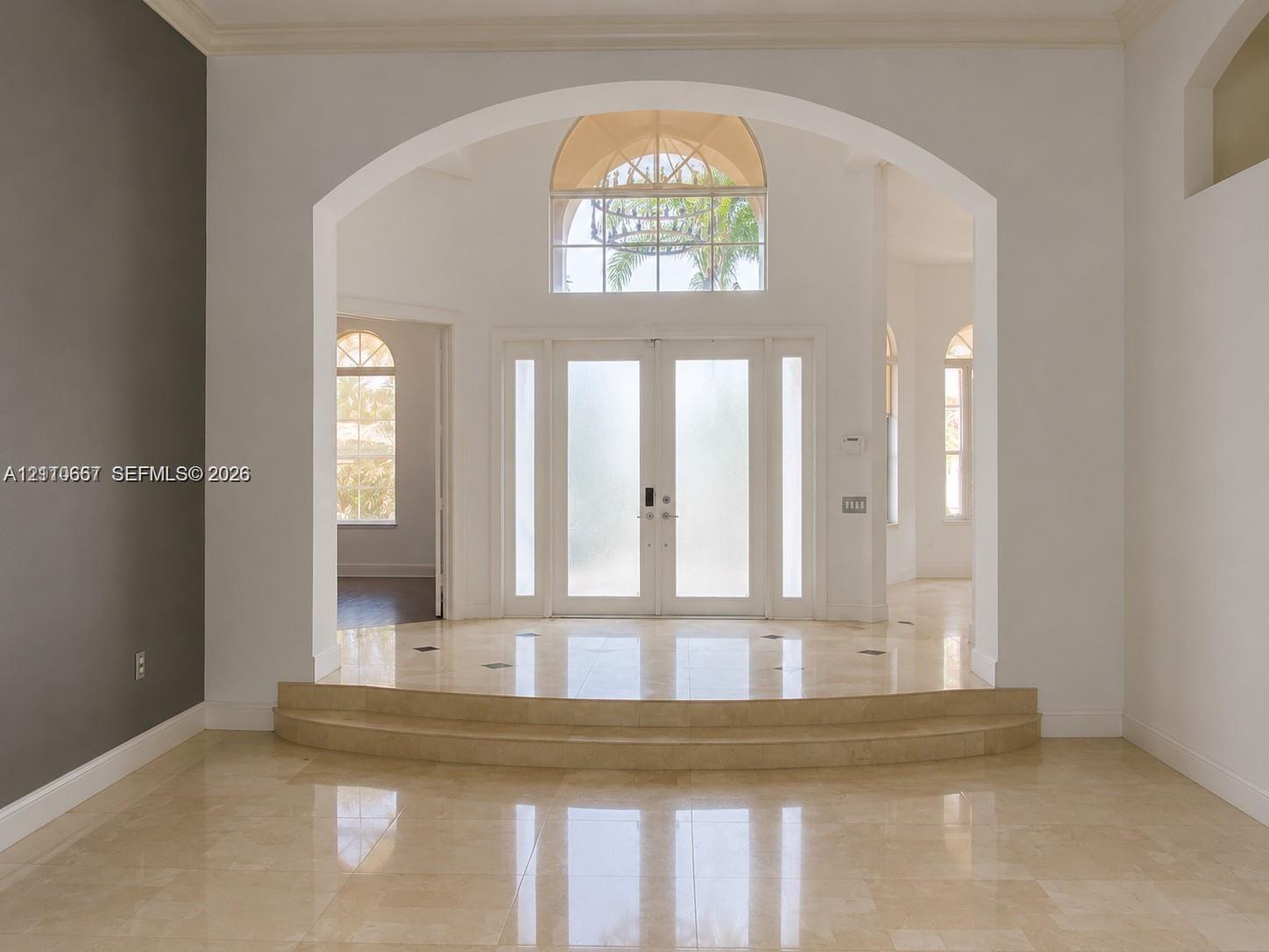 Living area featuring polished tile flooring, a recessed tray ceiling with integrated lighting, and a floor-to-ceiling picture window overlooking a swimming pool and greenery